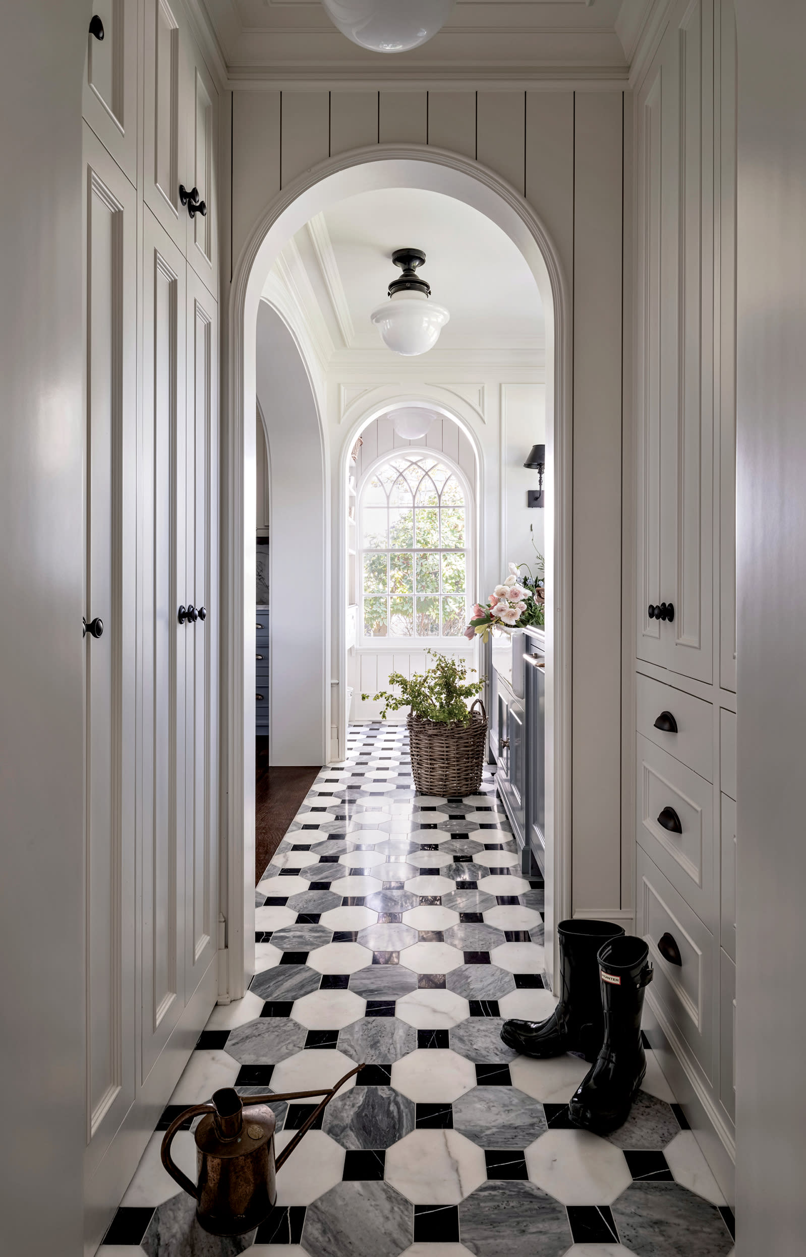 hallway with black and white geometric flooring and an arched doorway at the end of the hall