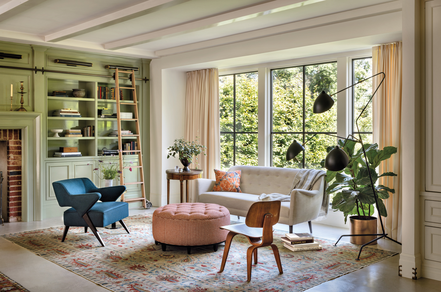 colorful living room area with light green built-in cabinetry, a brick lined fireplace, houndstooth print ottoman, vintage Eames chair and sofa