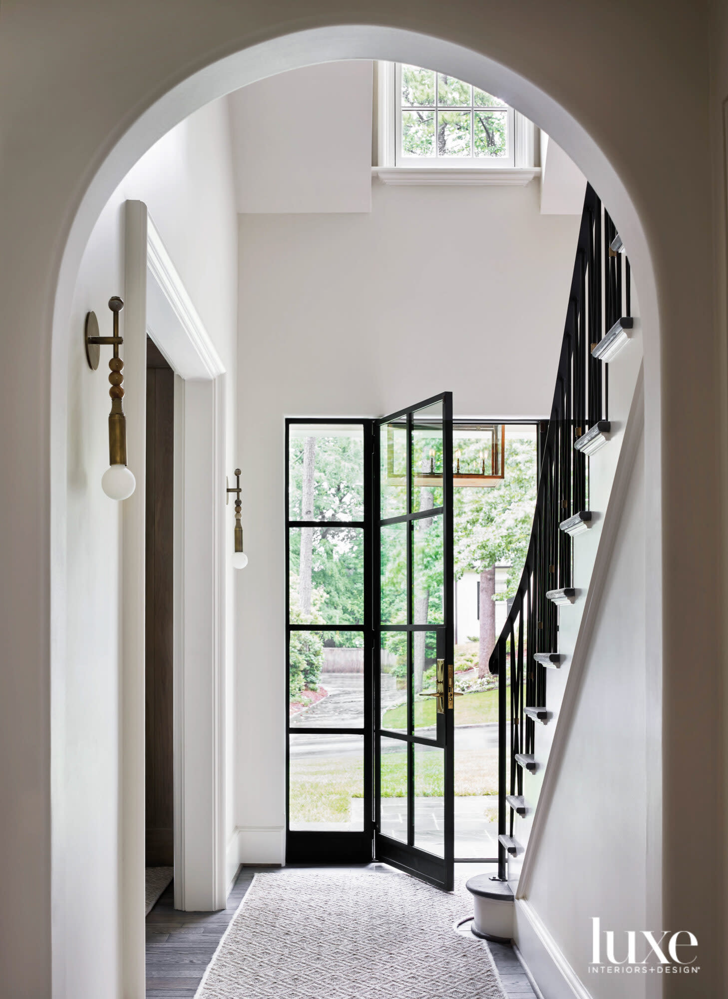 Bright entryway with iron-and-glass front door and modern sconces