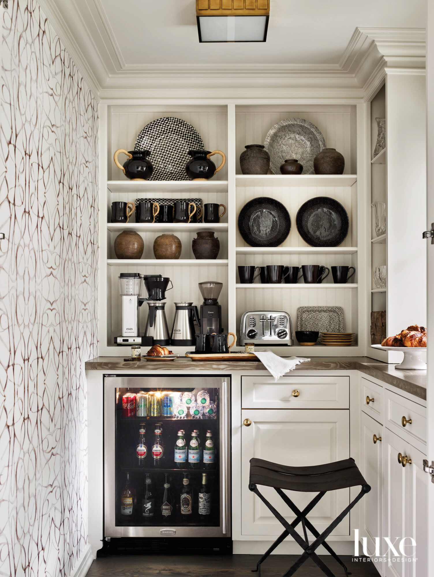 Well-appointed pantry with patterened wallpaper, built-in display shelves and creamy paint color