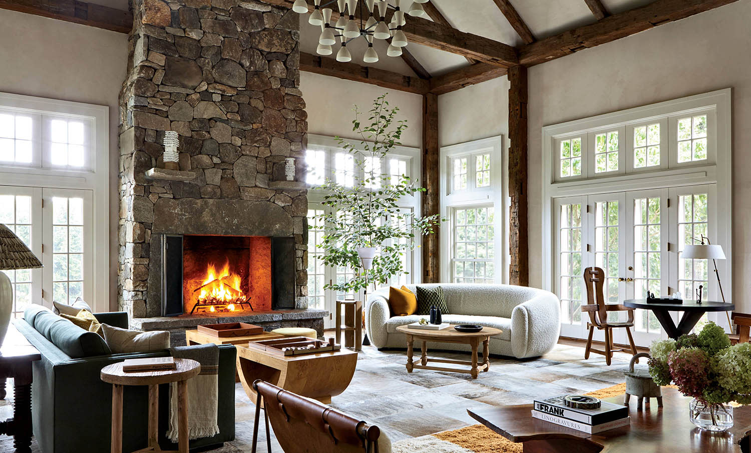 A fireplace with a roaring fire sits at the front of a living room sitting area.