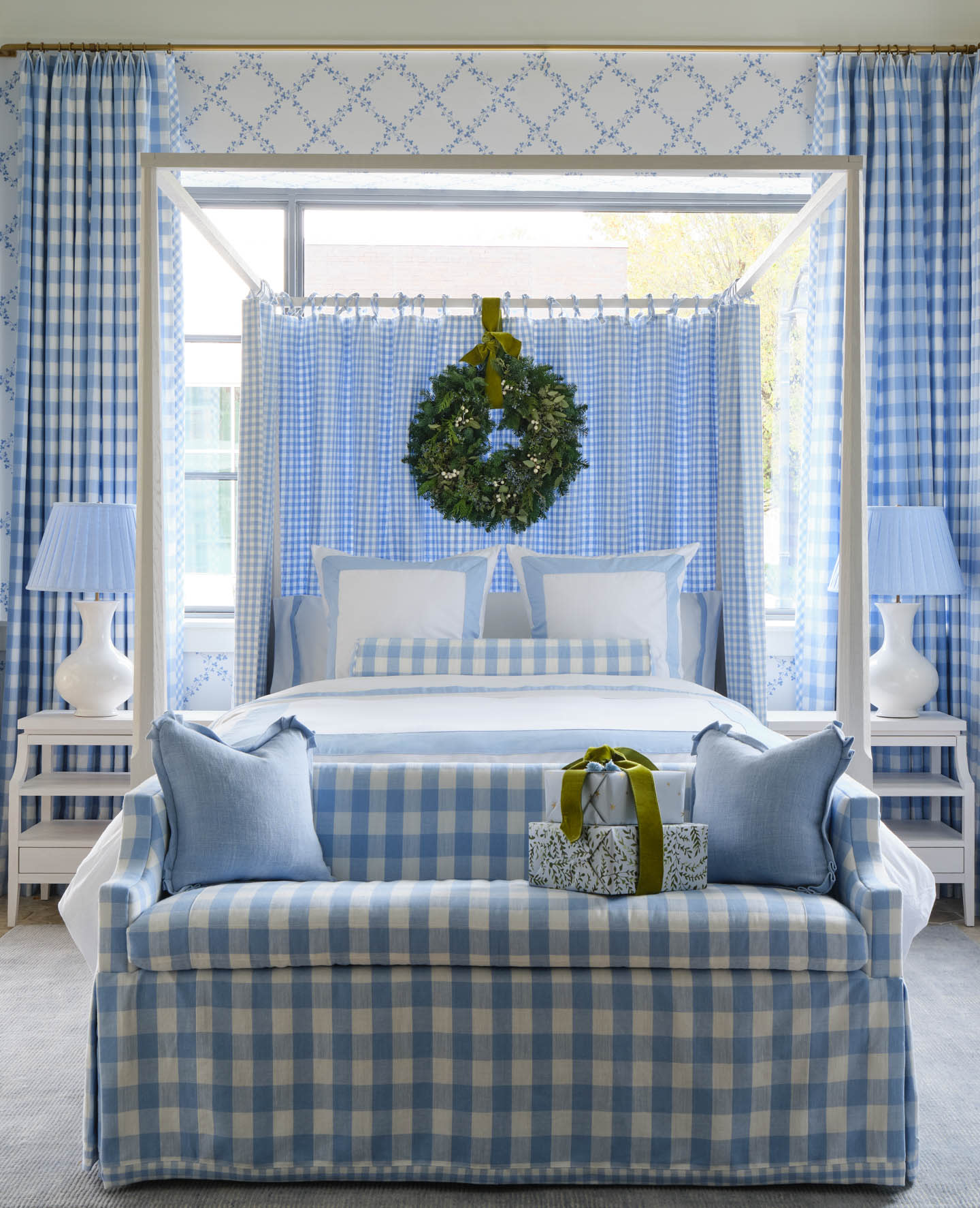 blue and white gingham drapes match a sofa at the end of the bed ad a wreath hangs above a headboard