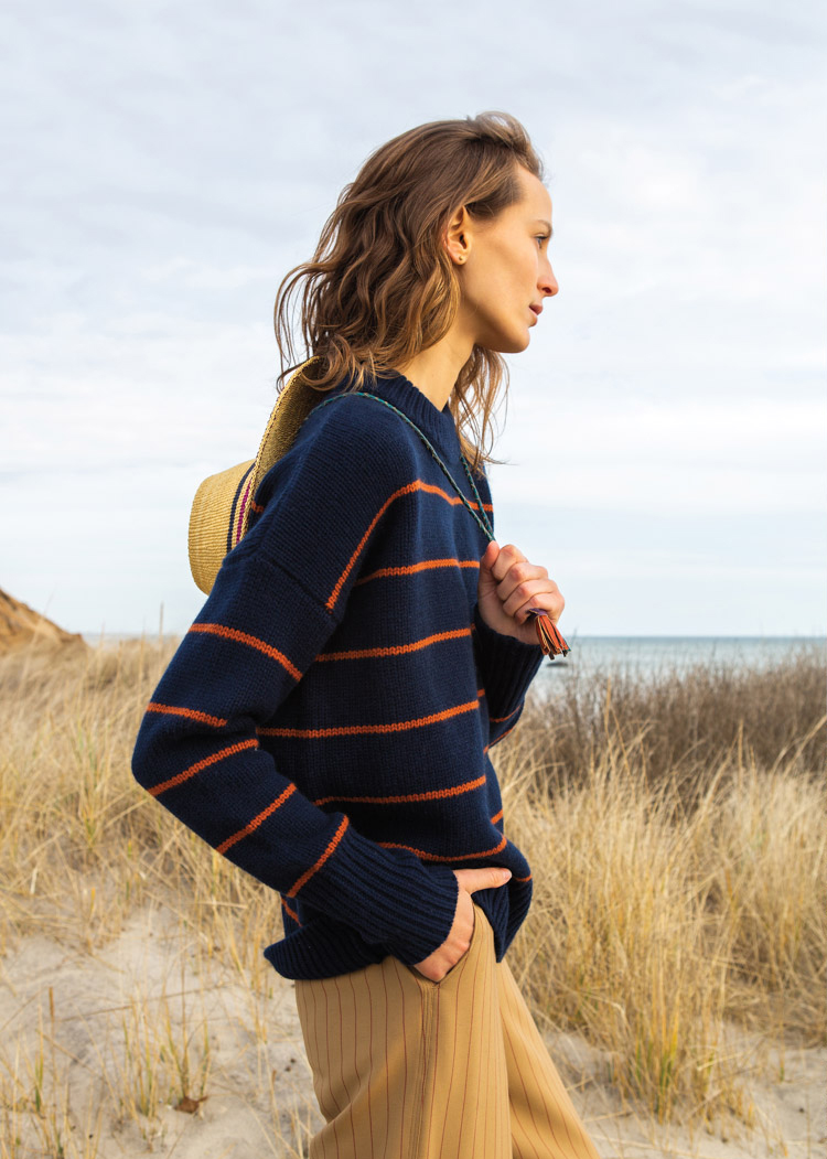 woman on beach in navy and red striped sweater
