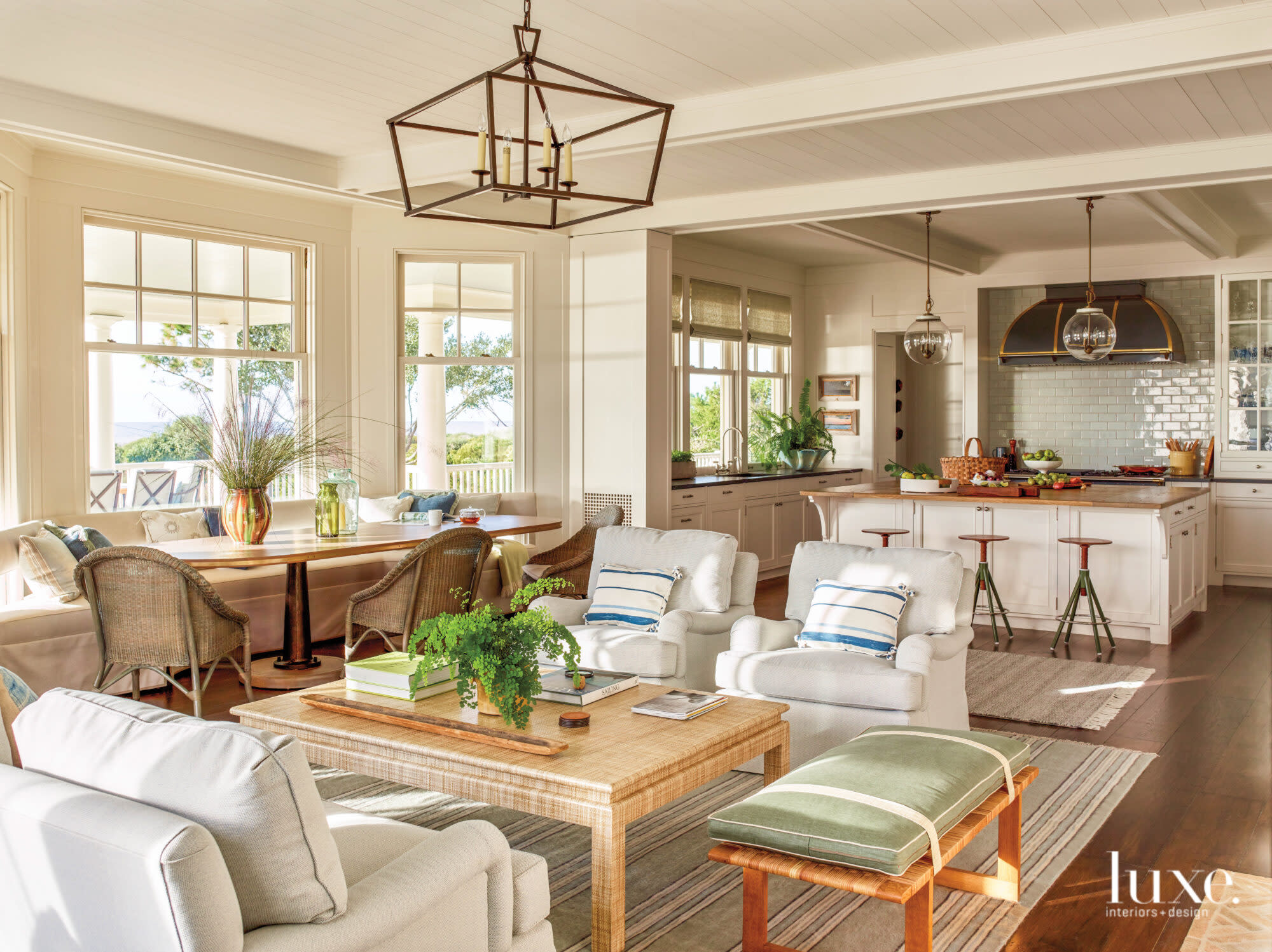 Armchairs surrounding coffee table with breakfast table and kitchen in the background
