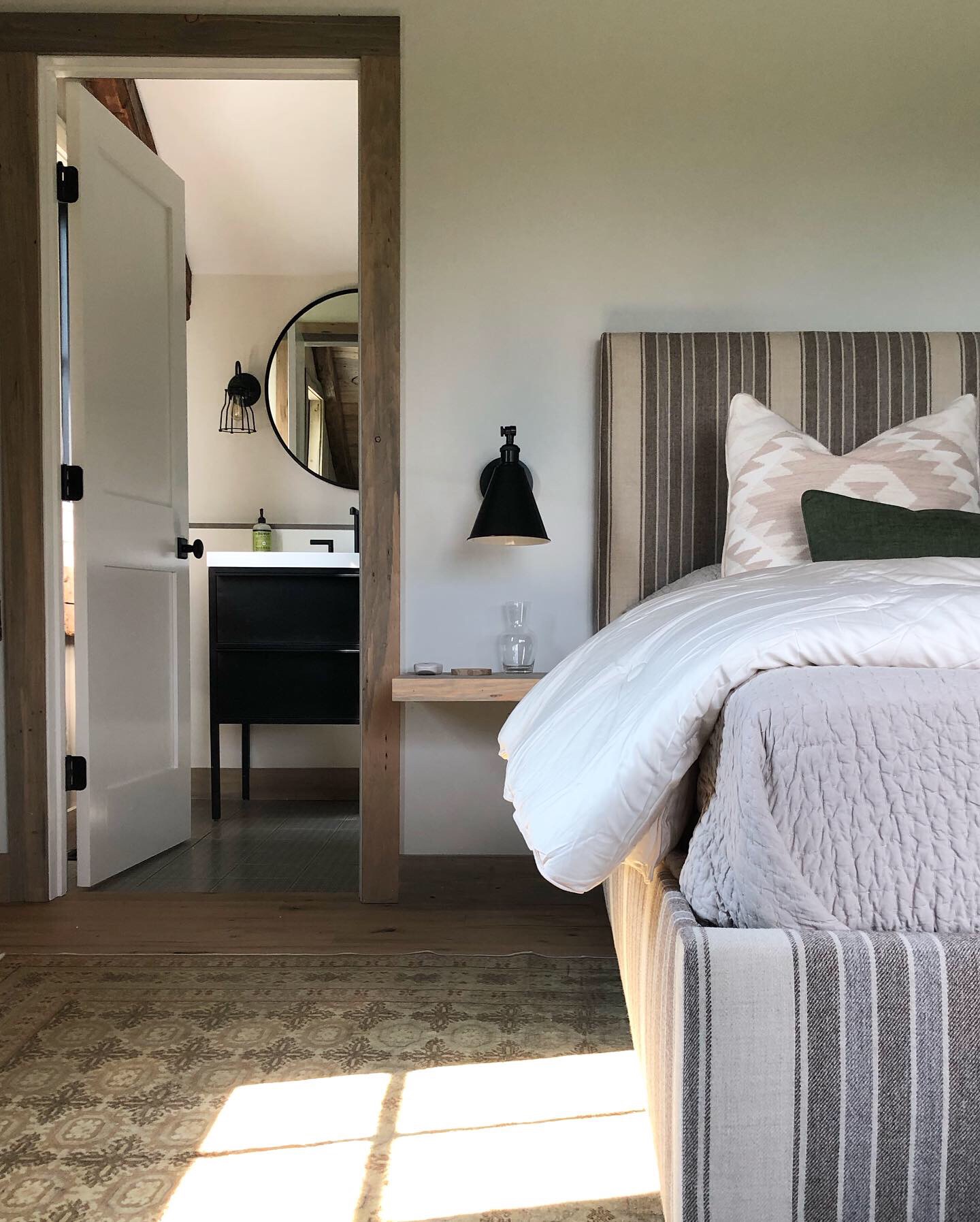 A bedroom with gray walls and an upholstered bed in a striped gray fabric.