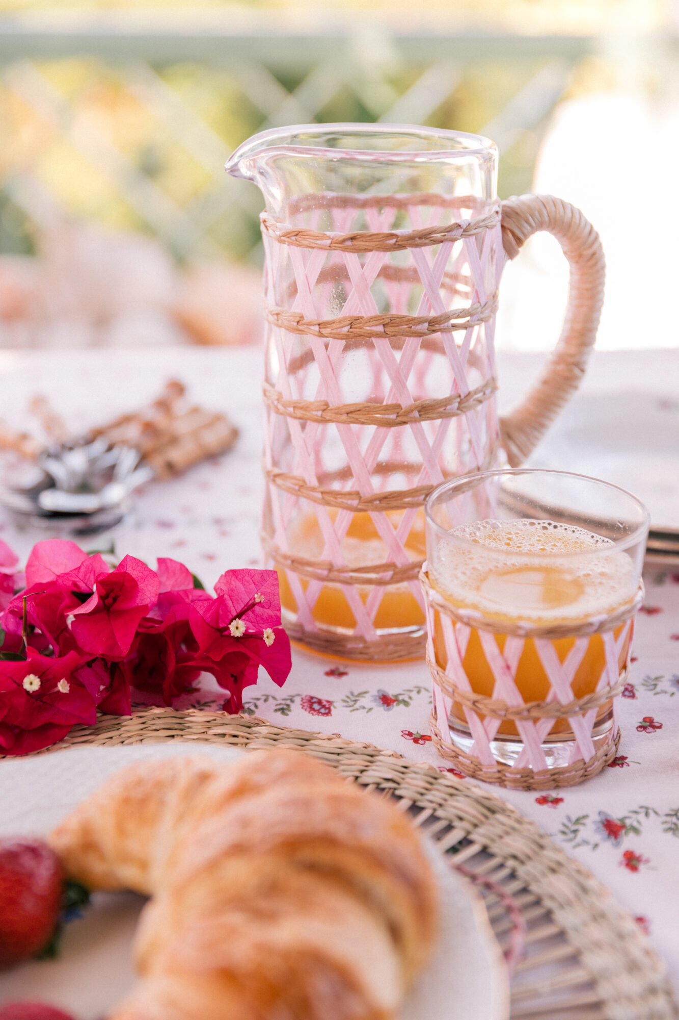 Blush-colored, rattan-detailed cups and pitchers dot the table