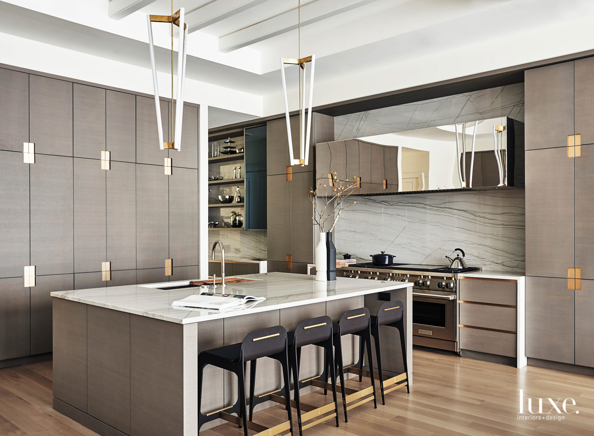 The bespoke kitchen has gray cabinetry and touches of black and brass throughout.