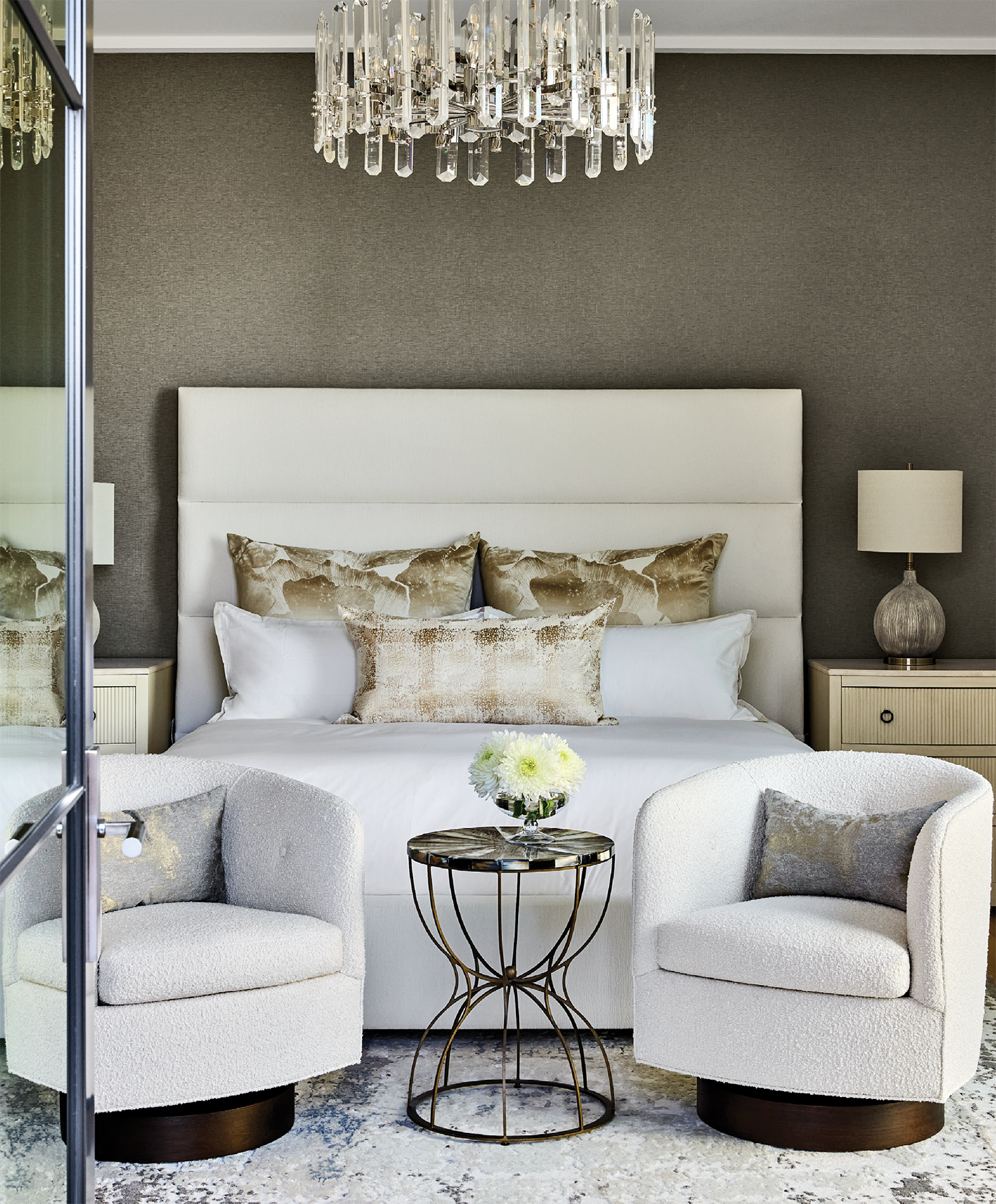 contemporary guest bedroom with a glass chandelier and boucle armchairs