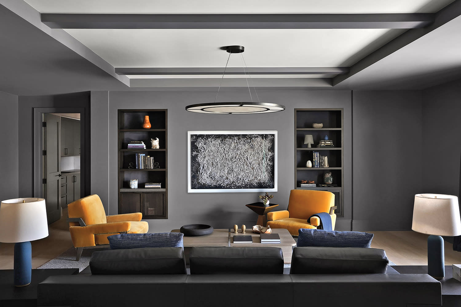 gray media room with a black sectional and yellow armchairs