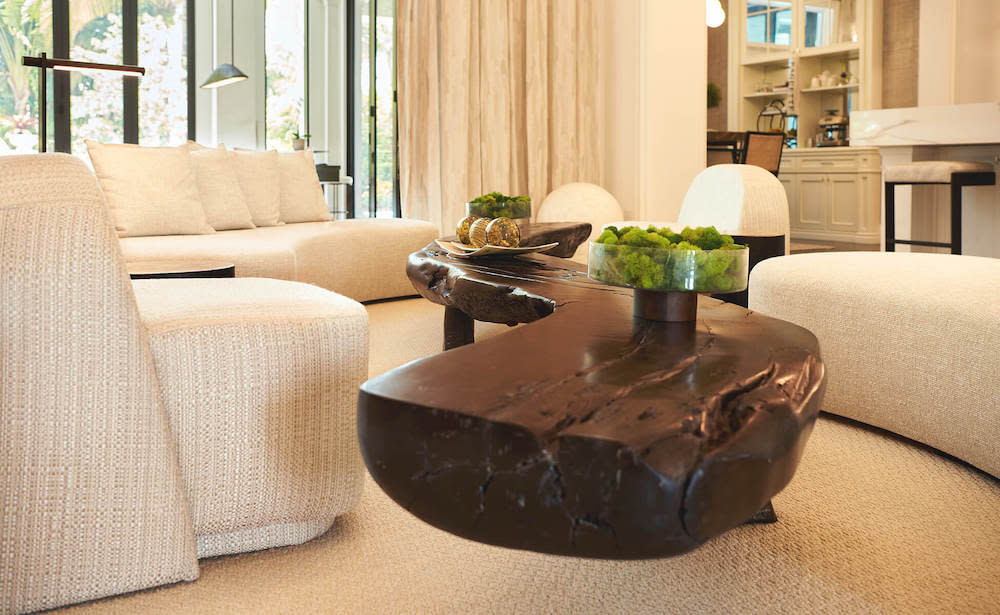 A bright living room featuring elegant white furniture and a stylish coffee table at the center.