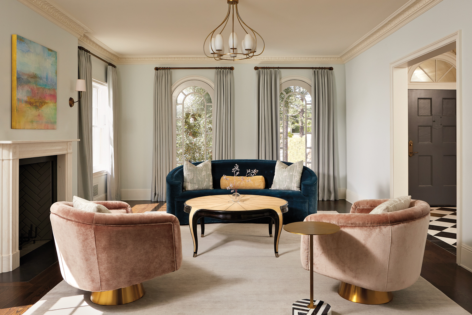 formal living area with curved blue sofa and pink swivel chairs and French style coffee table