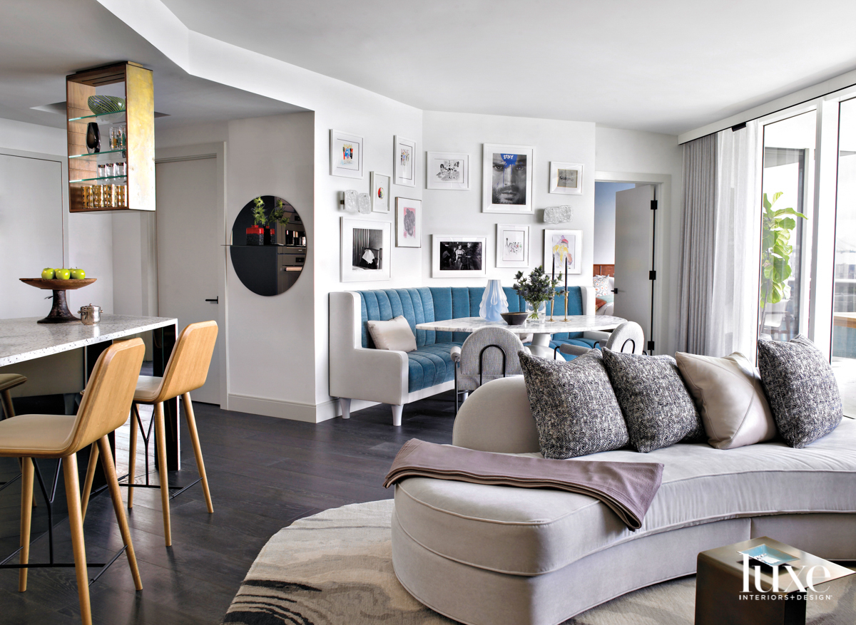 living and dining area with curvy sofa, blue banquette and wall artwork