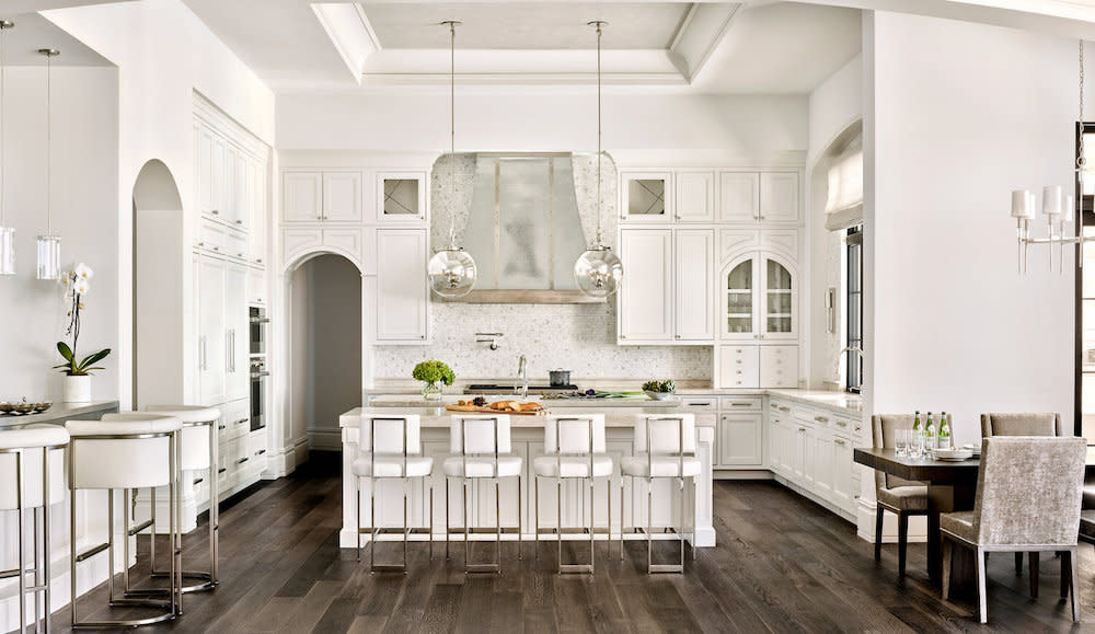 White kitchen with center island, steel hood and circular pendant lighting