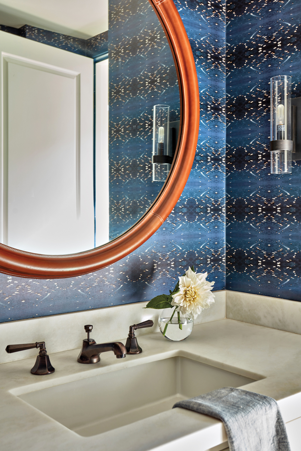 vanity with bronze finishes and blue wallpaper