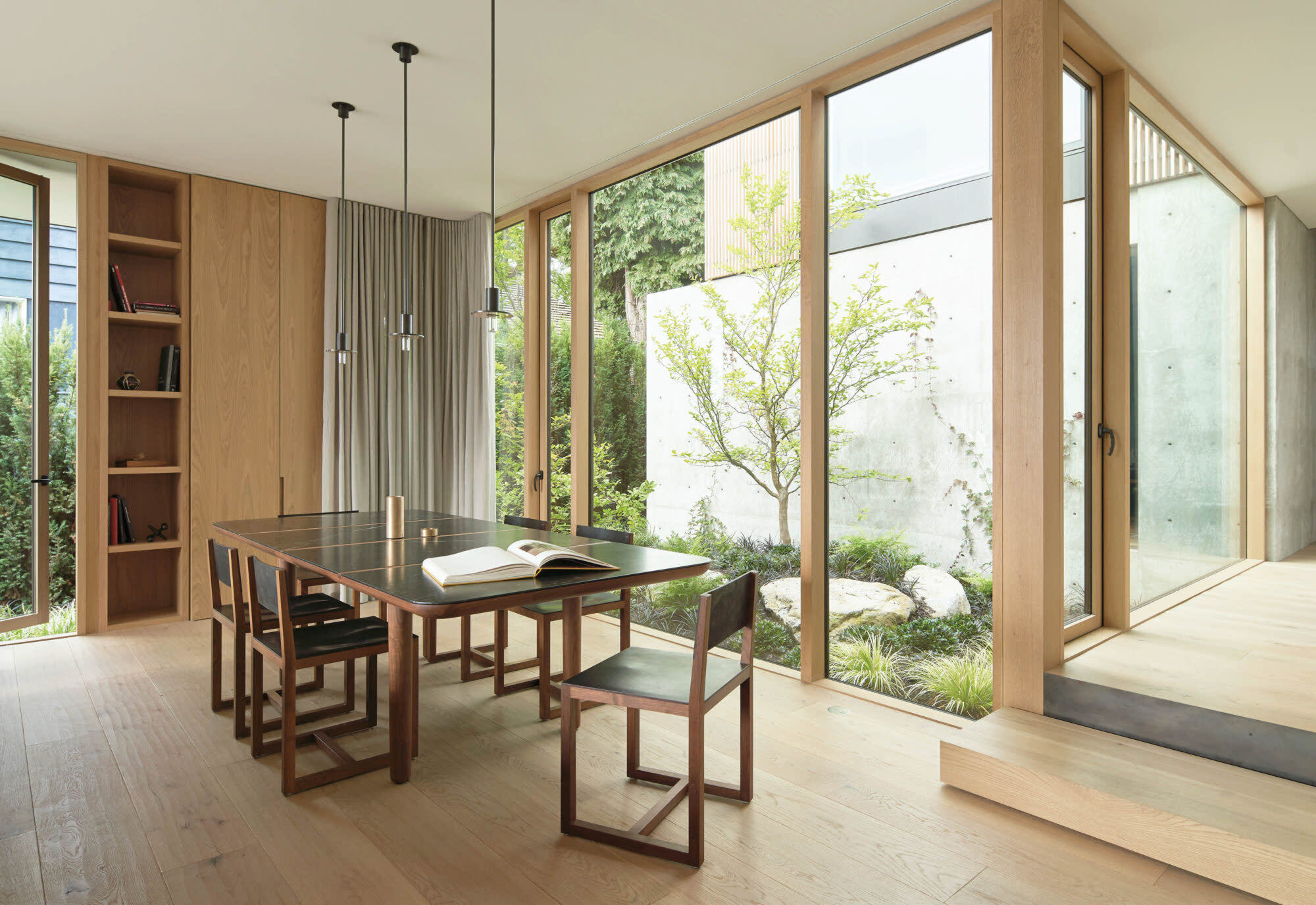 Dining room with light wood walls and floors, and large windows