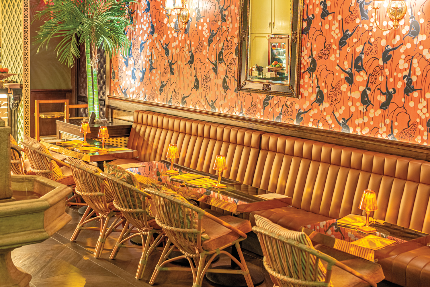 Cognac leather banquette seating and wicker chairs under orange wallpaper in Texas restaurant