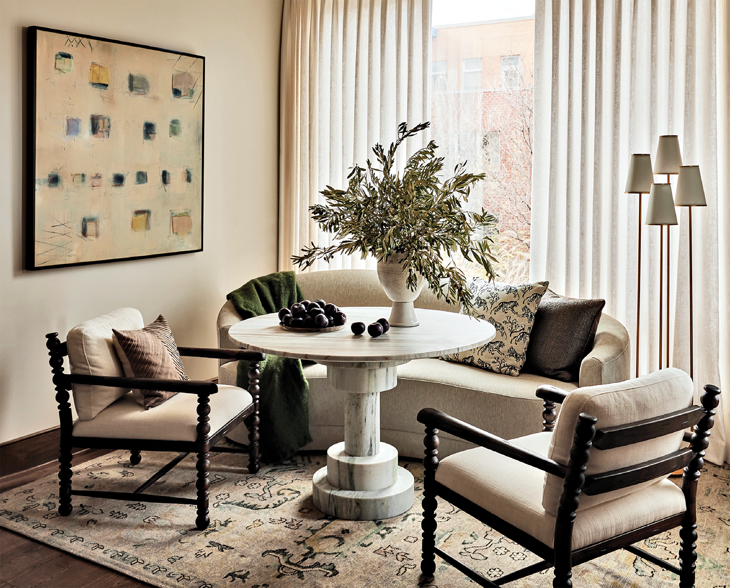 cozy breakfast nook with a sofa, marble table and midcentury chairs