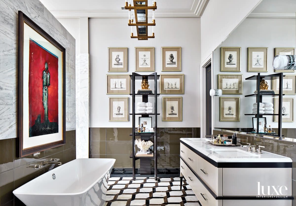 Dramatic and spacious bathroom with graphic marble floors, a standalone tub and framed artworks above a tiled wall