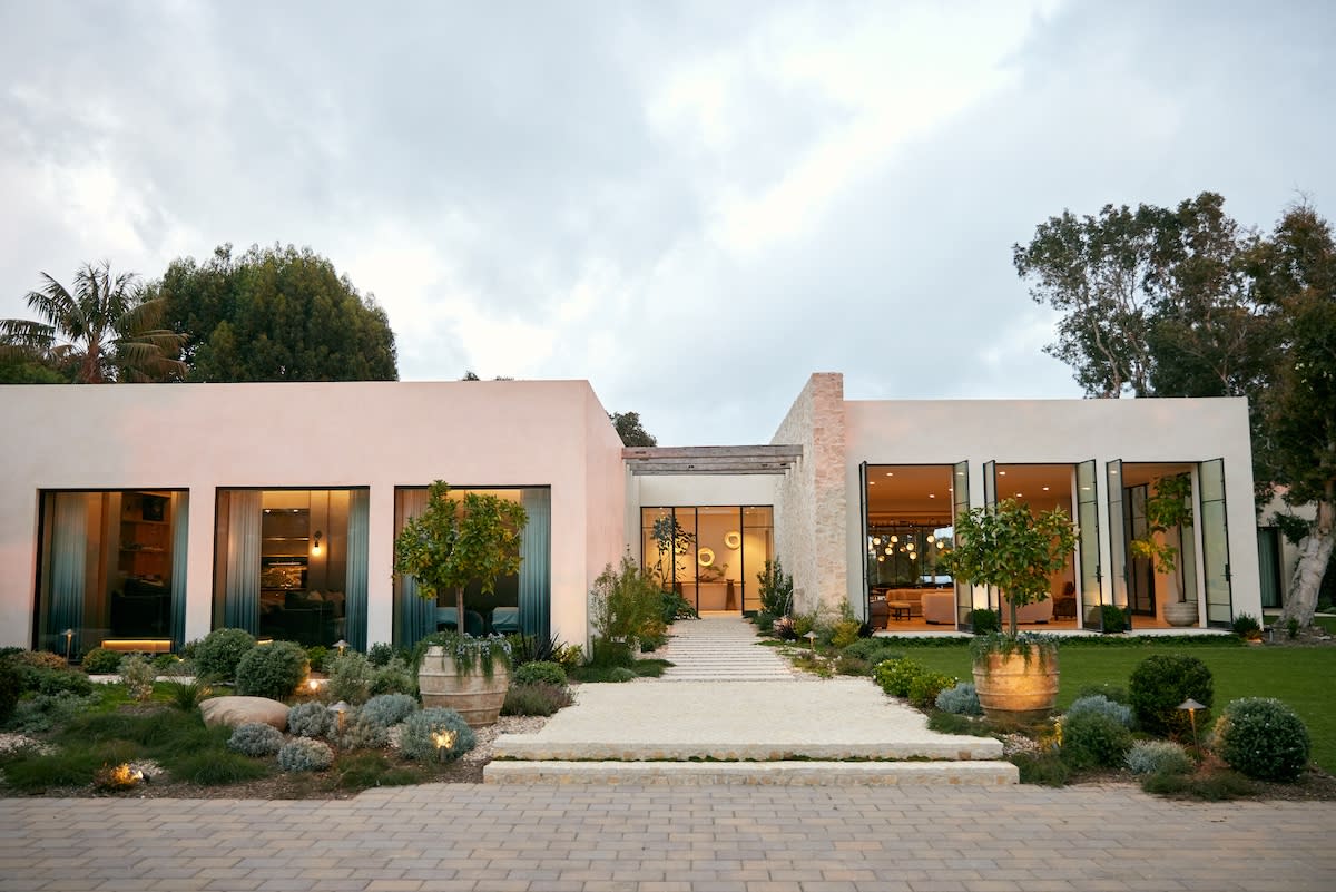 A stylish modern residence with an expansive driveway and lush landscaping.