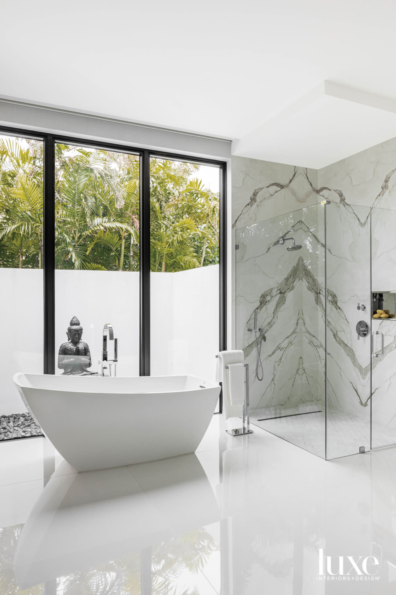 bathroom with freestanding white tub, white flooring, a marble shower and a Buddha statue