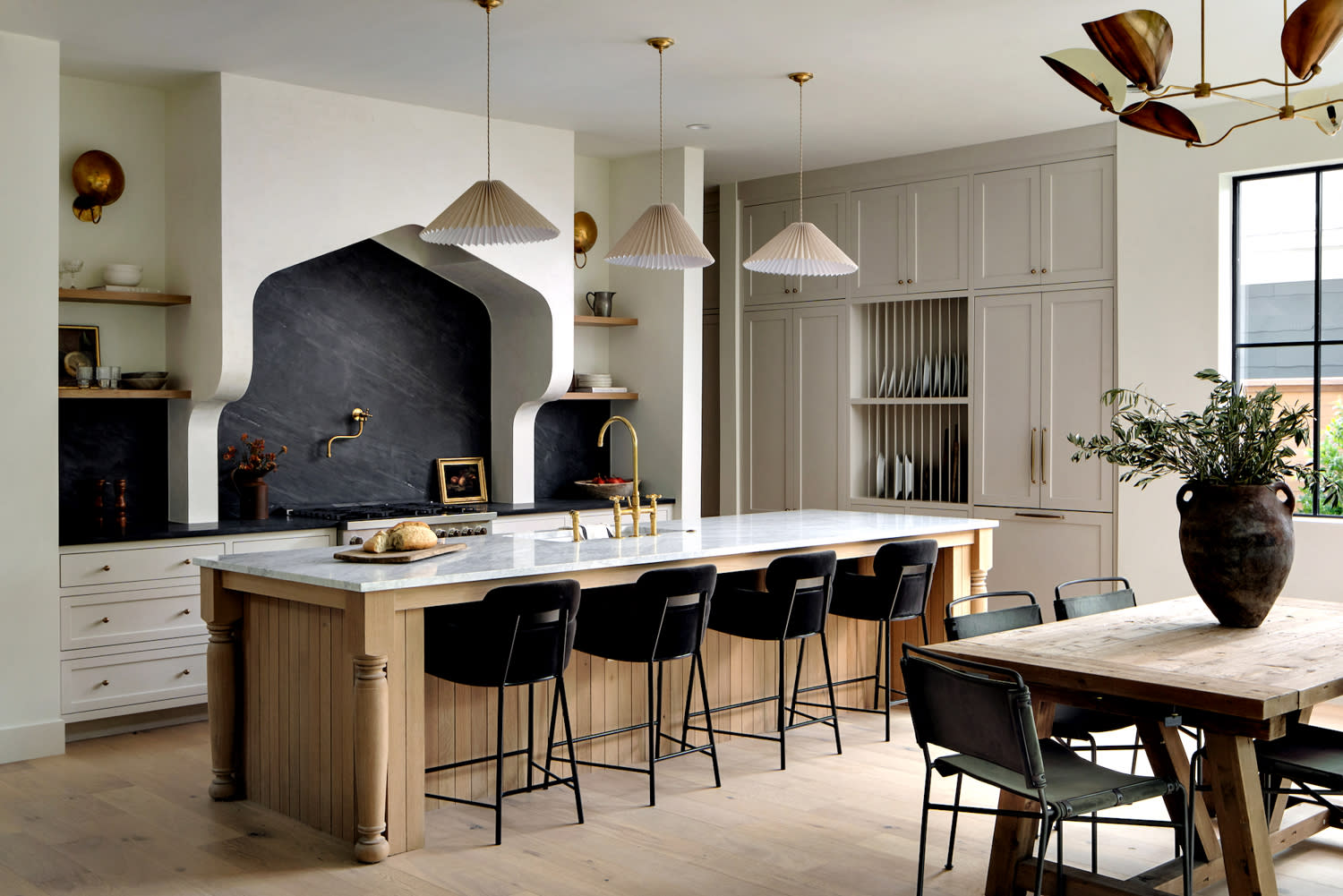 European-inspired kitchen with a black soapstone backsplash and pleated light fixtures