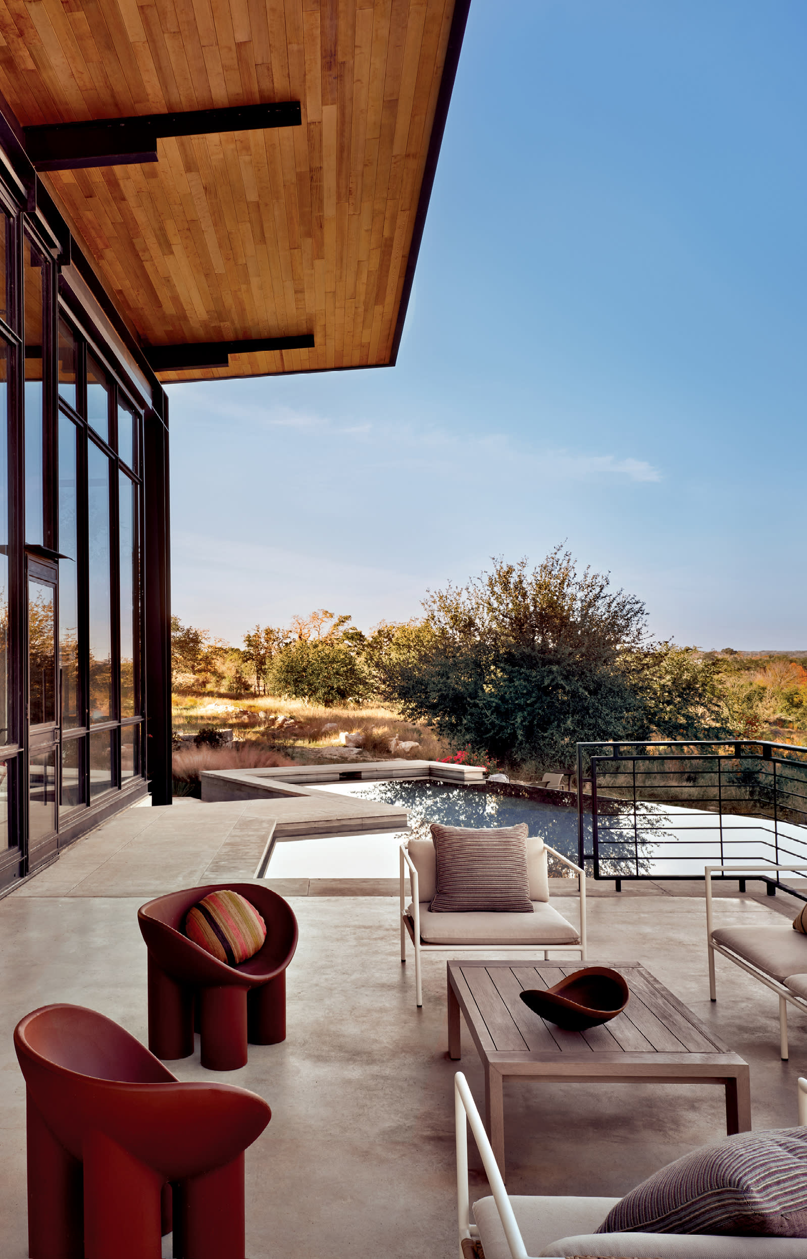 back exterior of a Brutalist home in Texas with a pool and various modern seating options