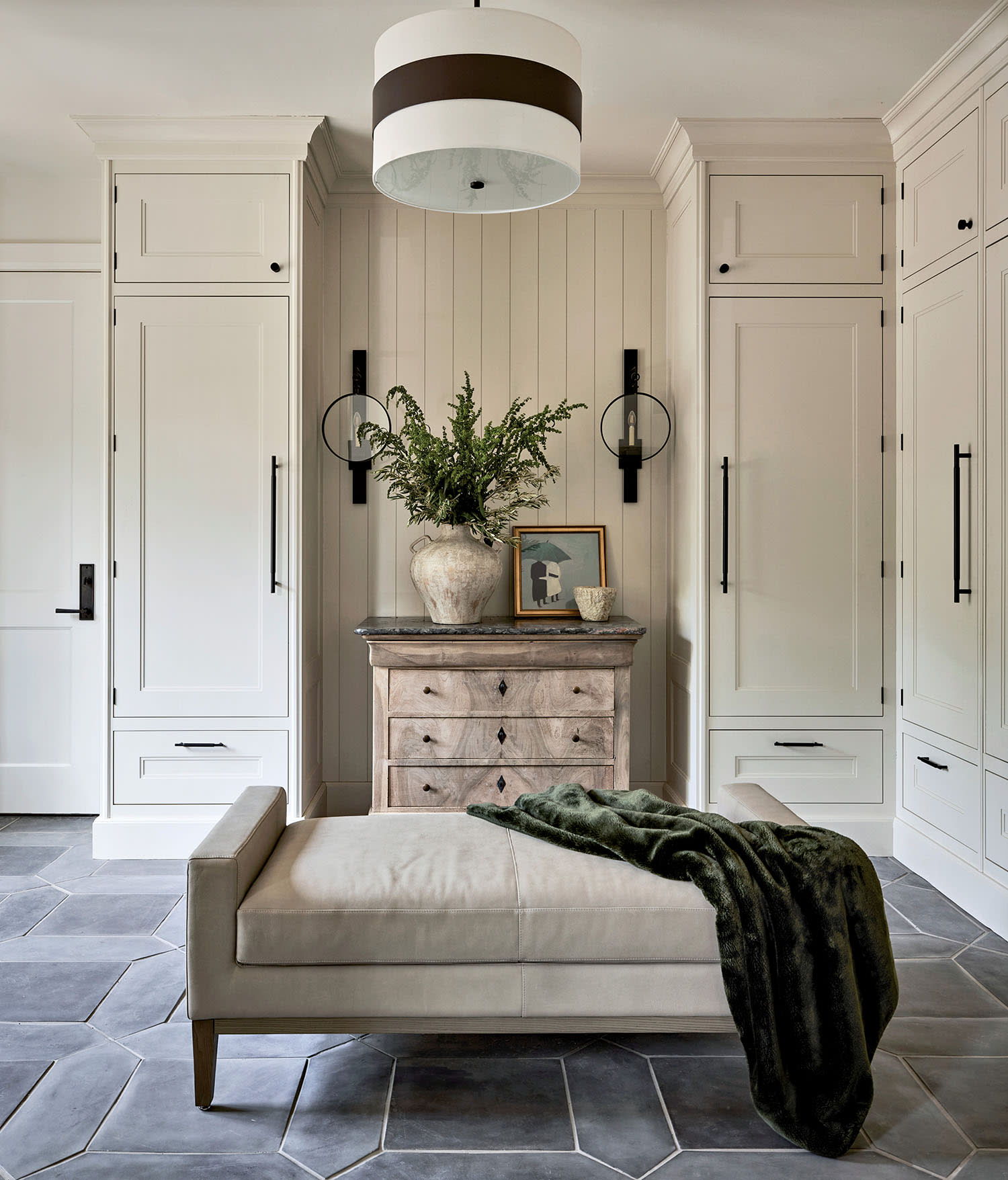 Elegant mudroom with cream cabinets, a wooden chest, and hexagonal tile flooring.