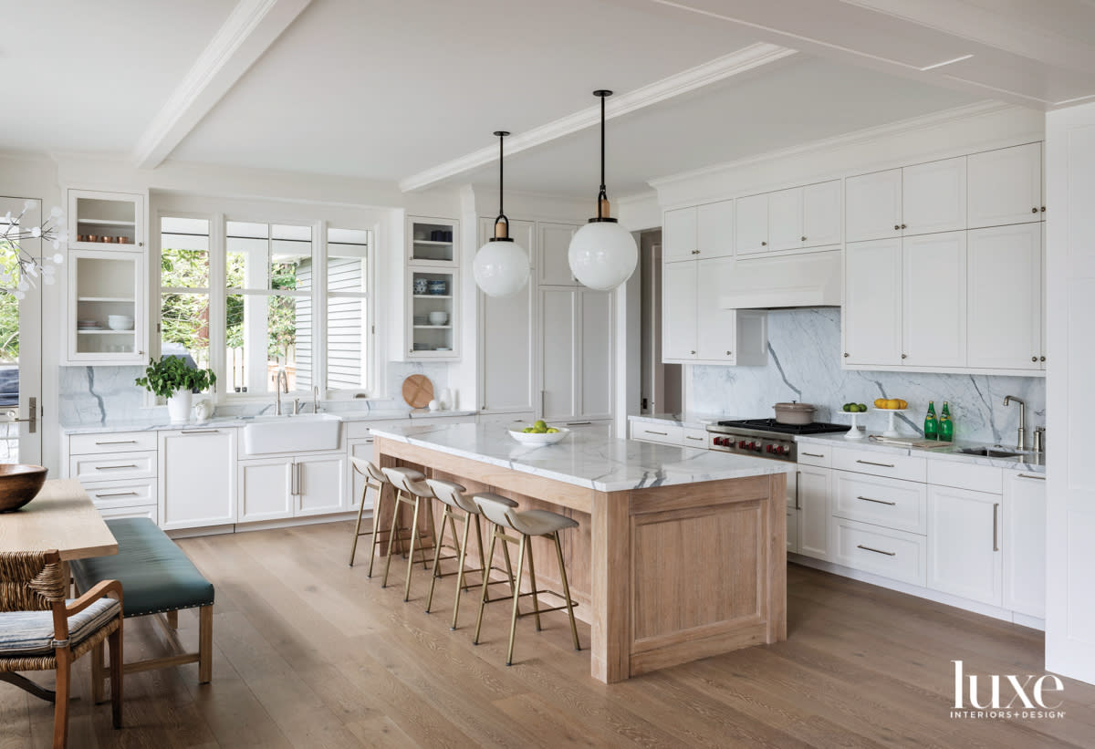 white kitchen with wood island and globe pendants