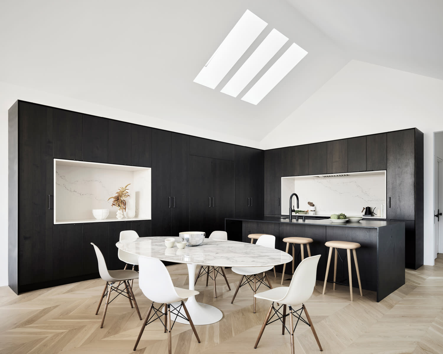 sleek open concept kitchen and dining area with black cabinetry