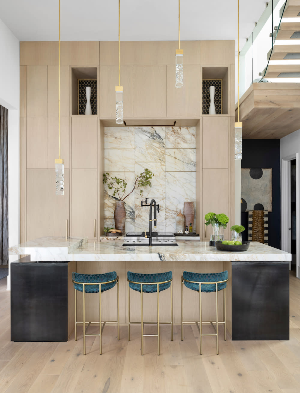 Large kitchen with high ceilings and light brown cabinets and gold pendant lighting by Construction Resources