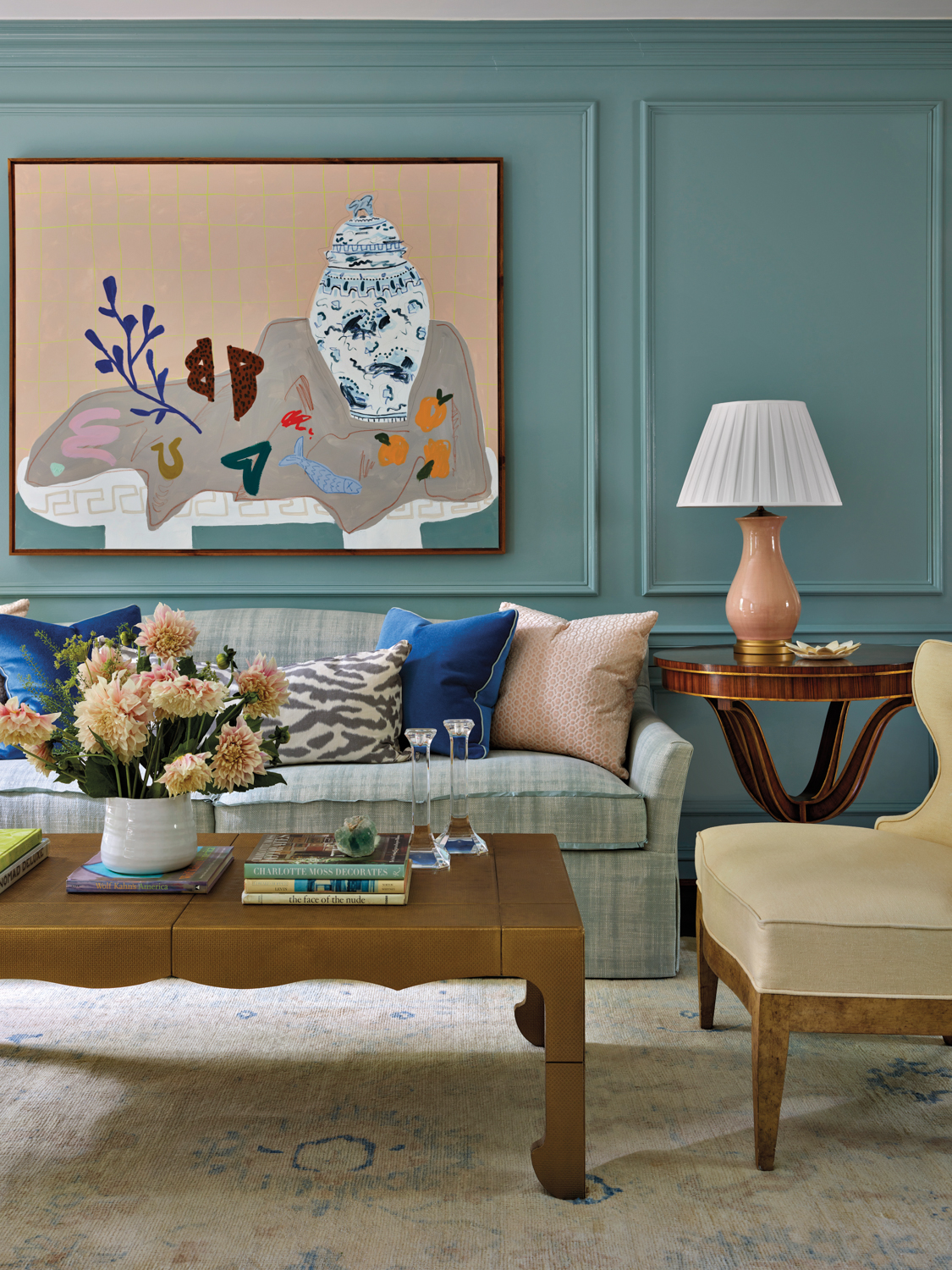 Living room with a cozy sofa, scalloped coffee table and an abstract still life painting