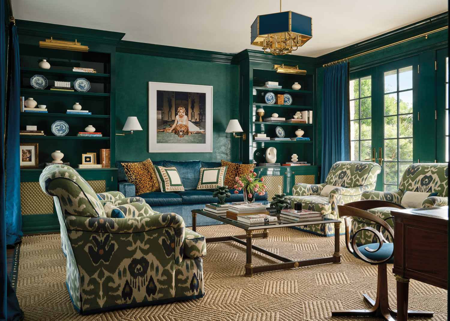 moody study with green-blue walls and floral-patterned armchairs