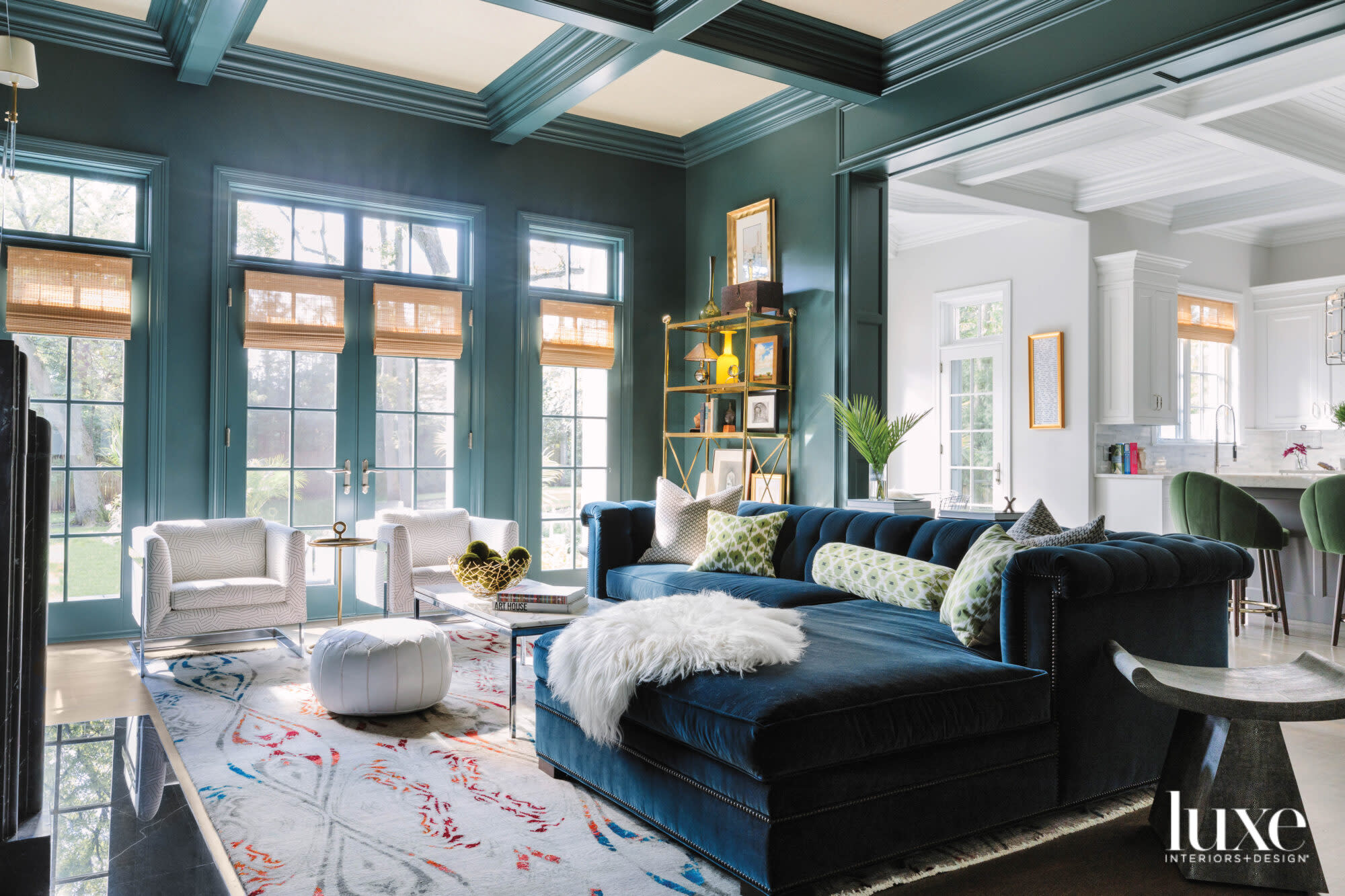 The family room has a a dark teal sectional. The walls and the ceiling beams are painted green.