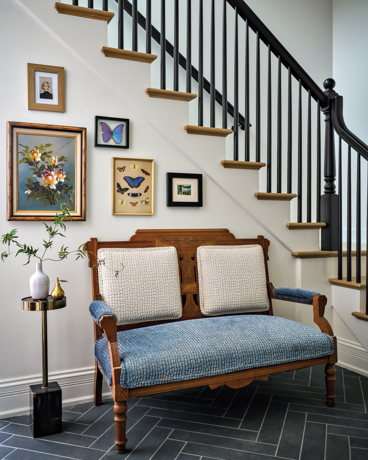 antique settee and side table beneath a gallery wall along the staircase