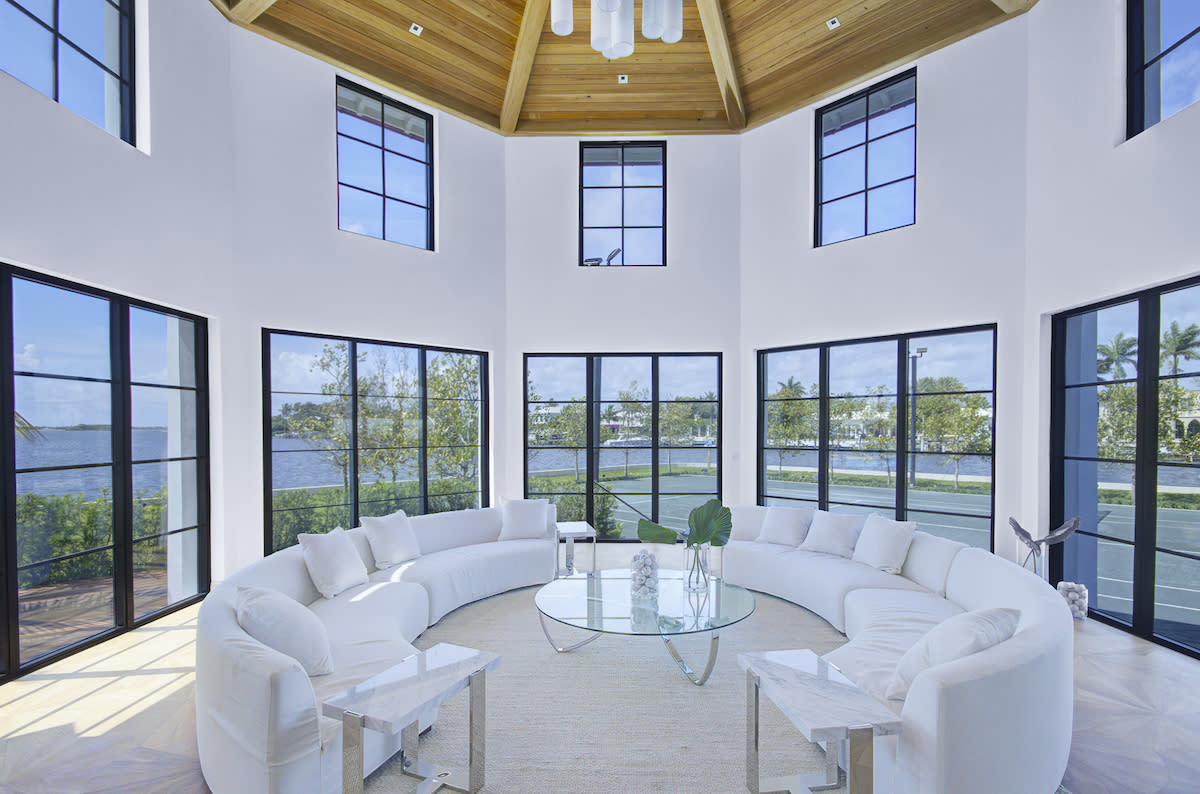 A circular living room with white furniture and windows, creating a bright and airy space.