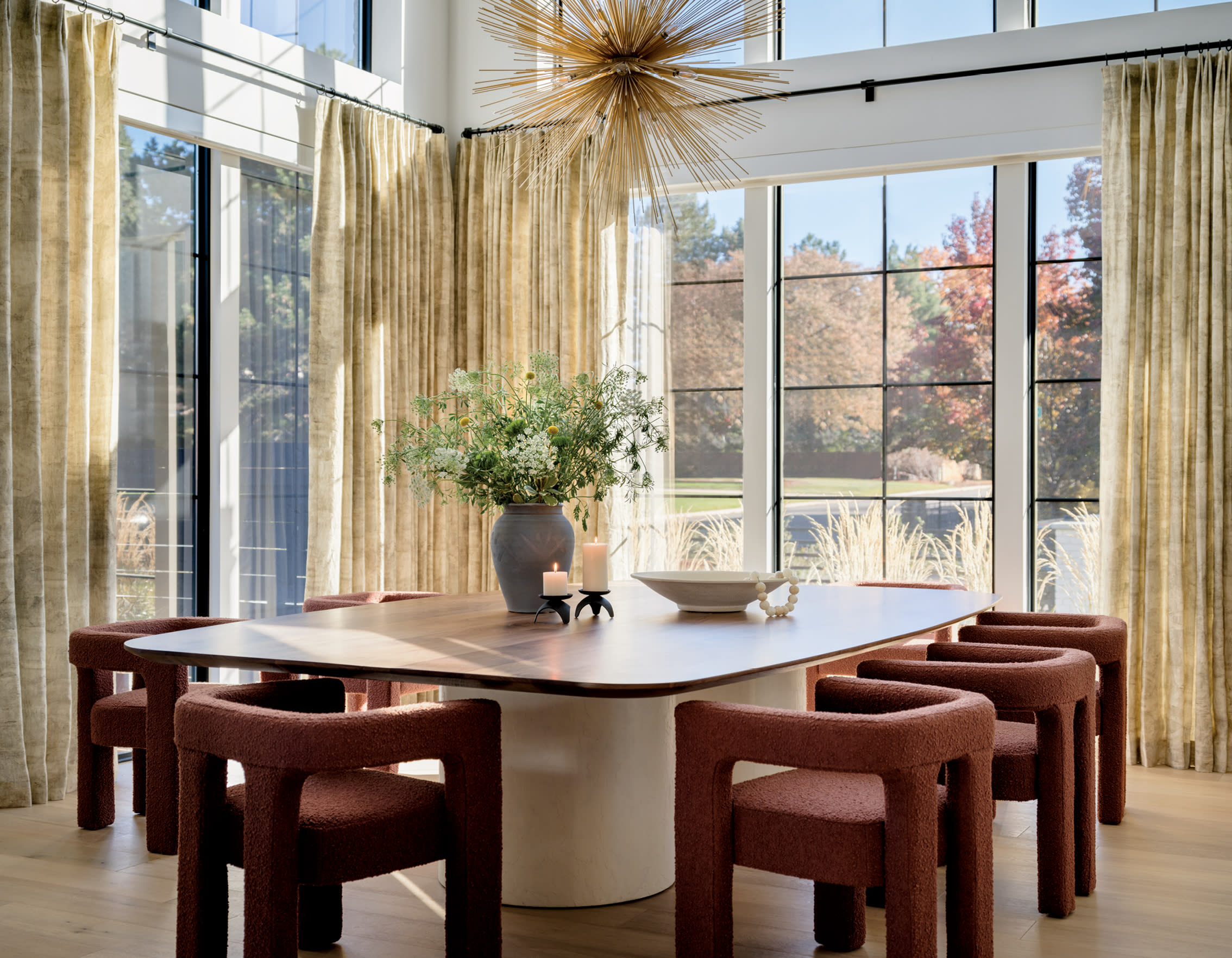 modern red dining chairs surround a dining table beneath a sputnik chandelier