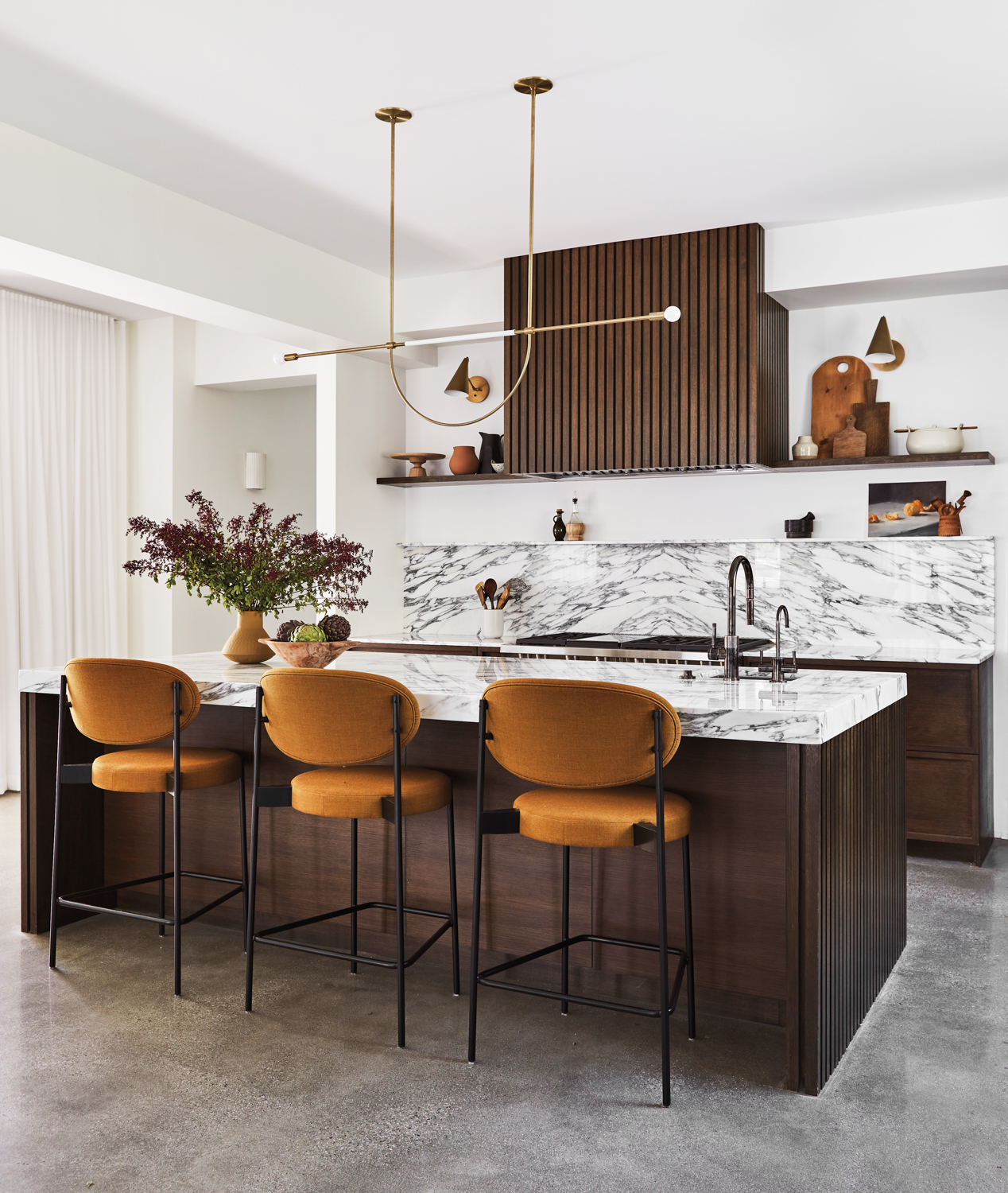 kitchen with a wood hood cover, marble counters and backsplash, leather pendant, and counter stools