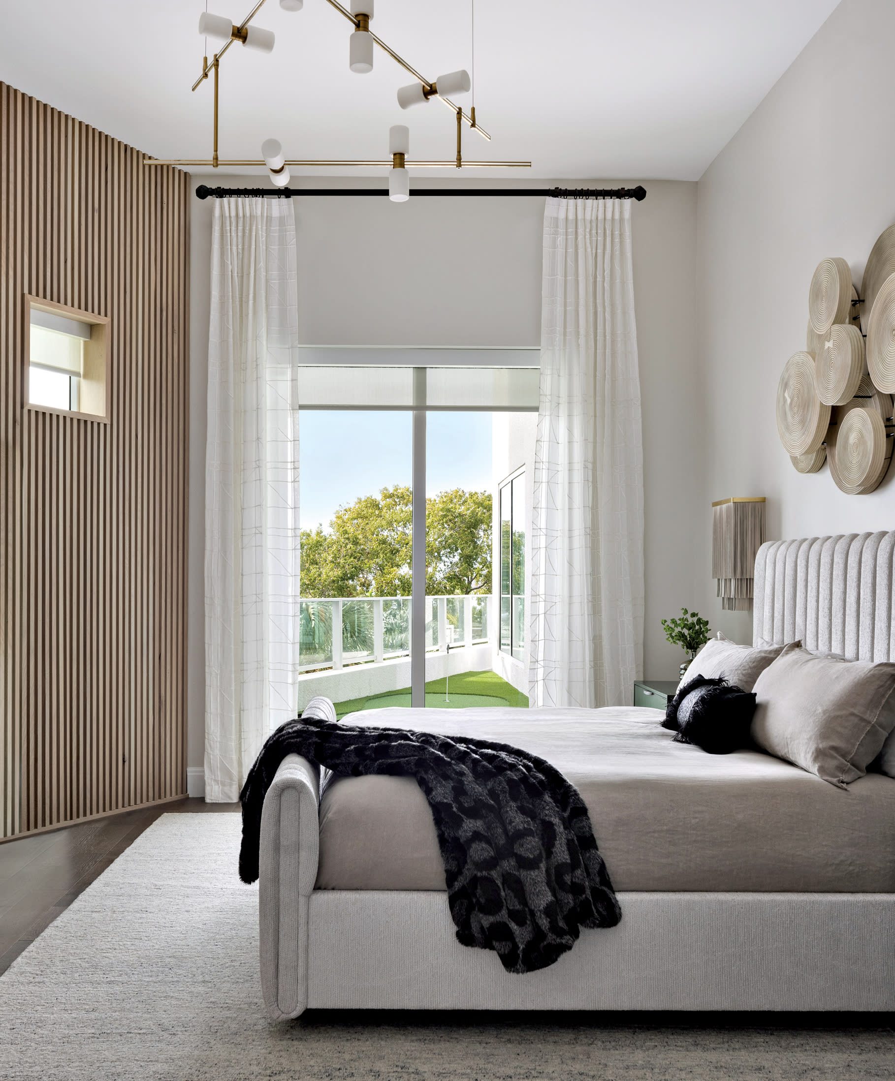 modern neutral bedroom with a curved reeded wall and gray linens