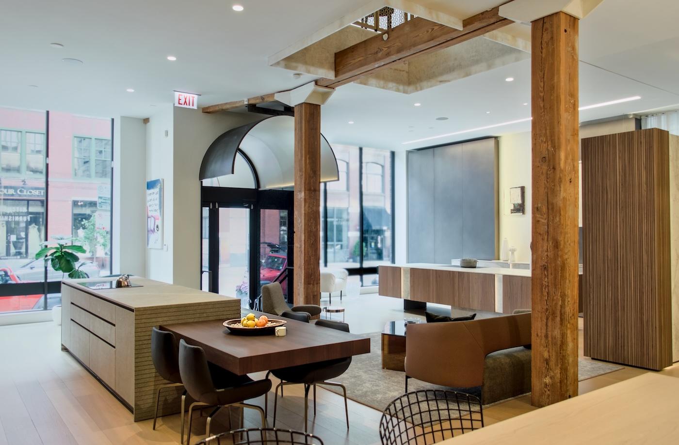 Modern, open-concept interior with high ceilings, wooden beams, and large windows. Features a kitchen area with a dining table and cozy seating, conveying a contemporary and inviting atmosphere.