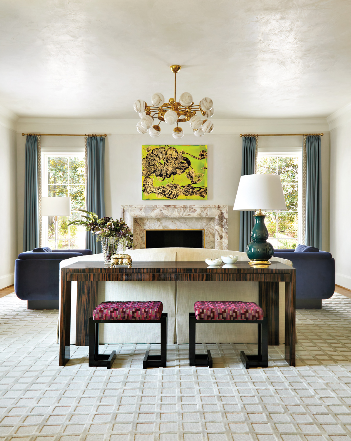 contemporary living room with cream plaster walls, colorful artwork, marble fireplace and chandelier