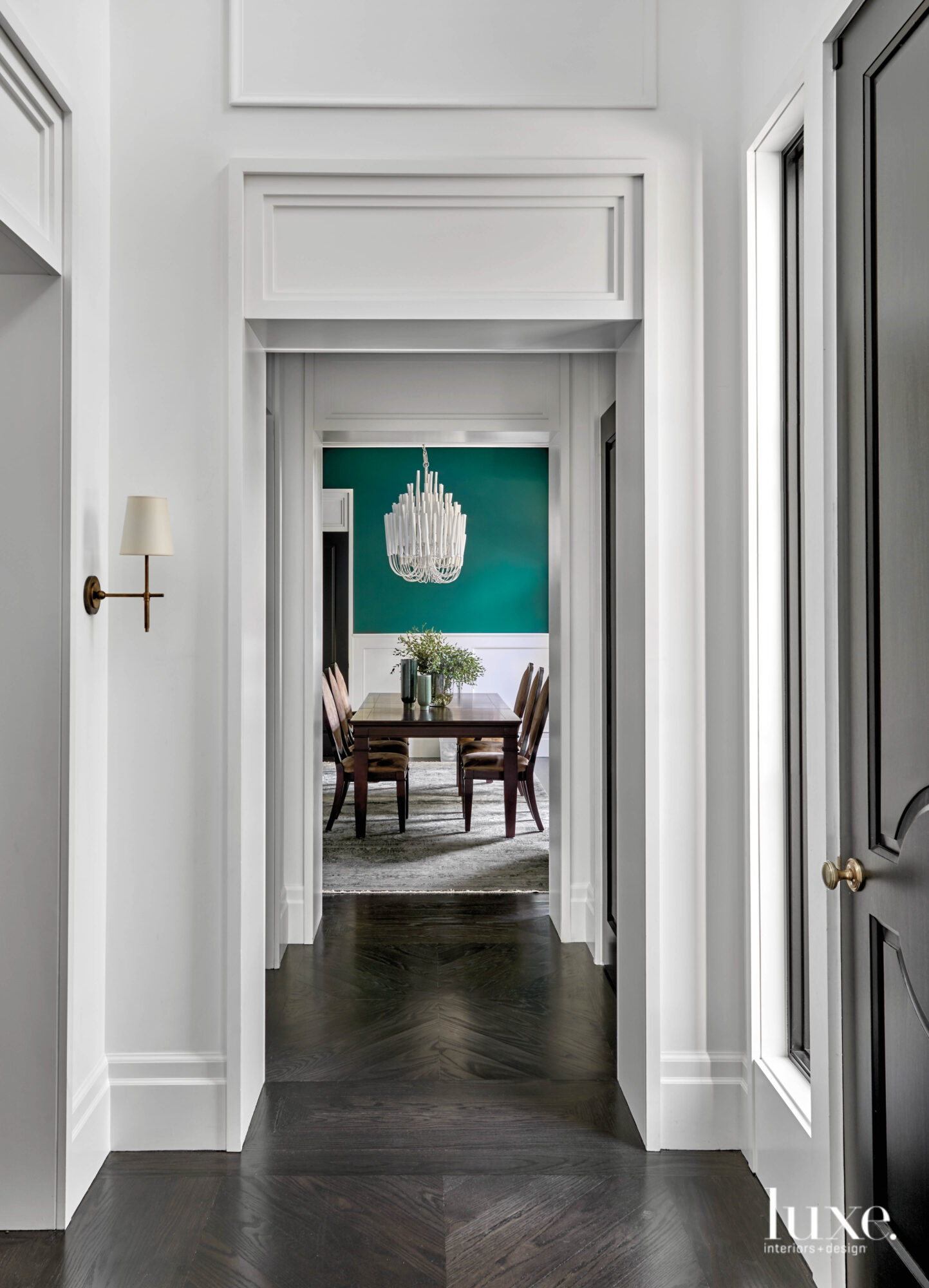 Dining room with teal green walls and a chandelier over the dining table.