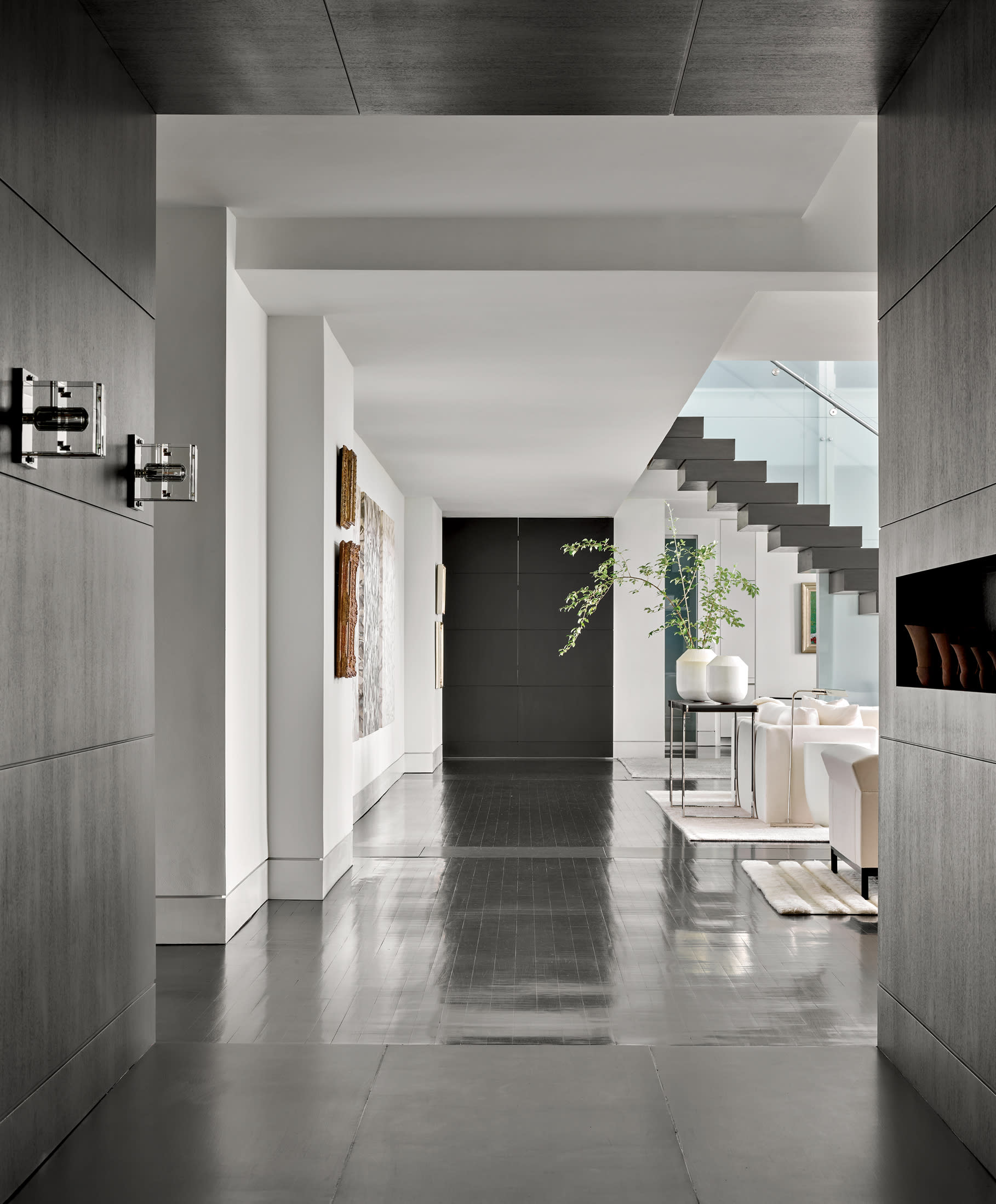 modern dark entryway including a glass staircase with dark treads