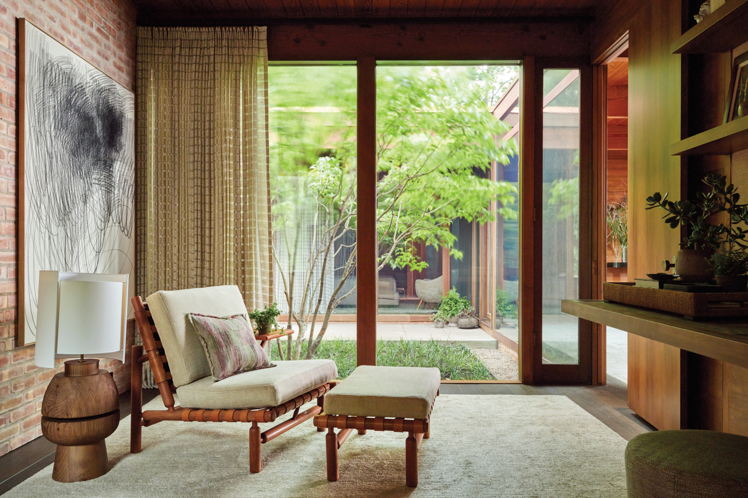 Wood chair with cream cushions atop a cream rug, set against a wall of windows