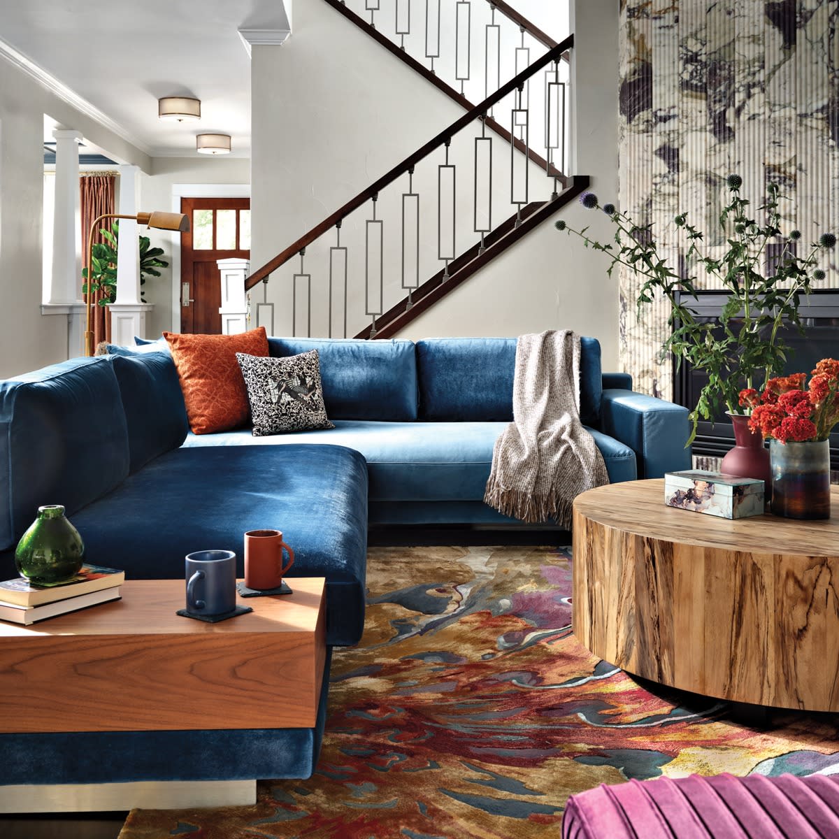 colorful living room with staircase in background and teal blue sectional