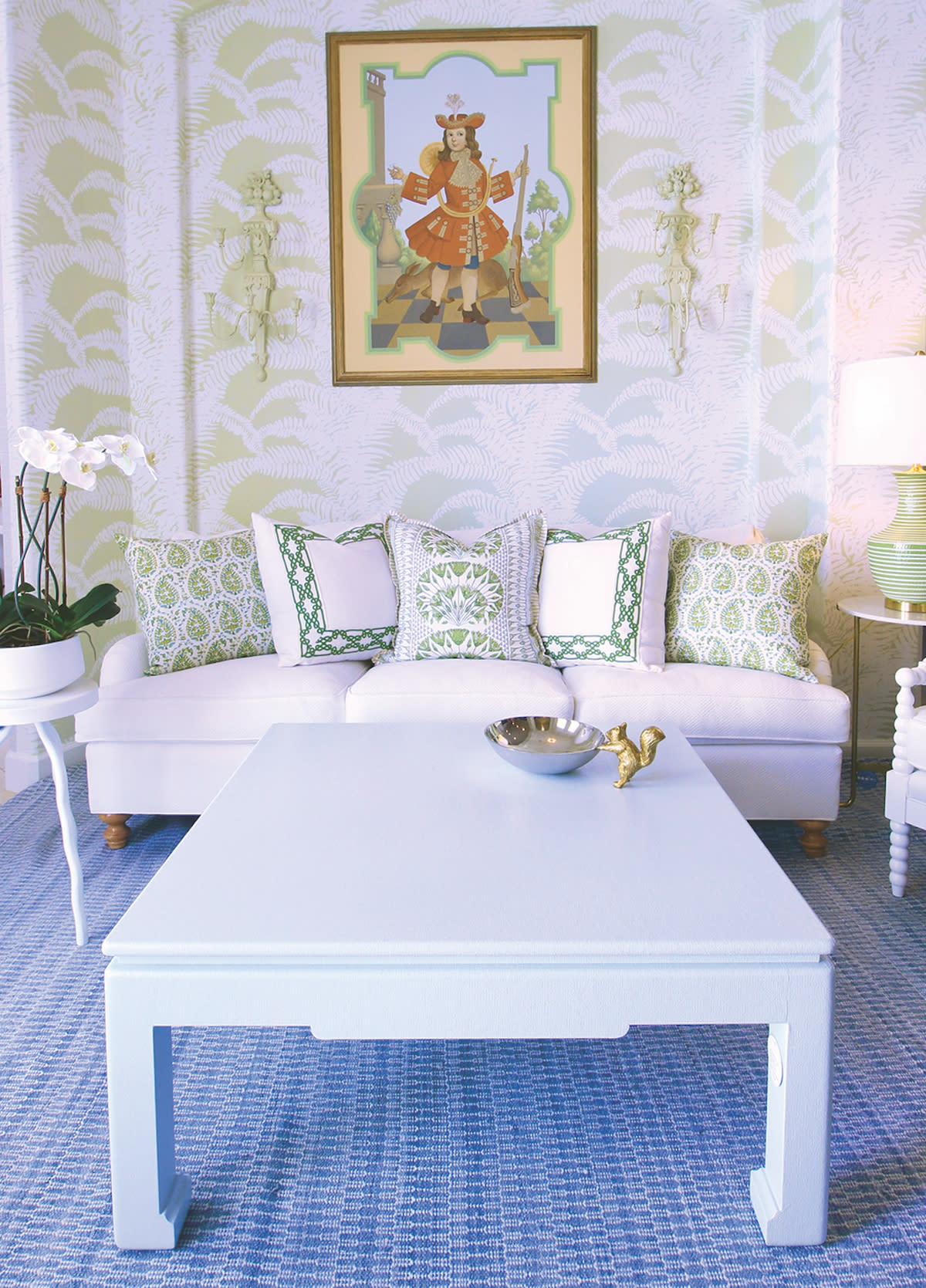 Green and white wallpaper, white coffee table, green and white pillows.