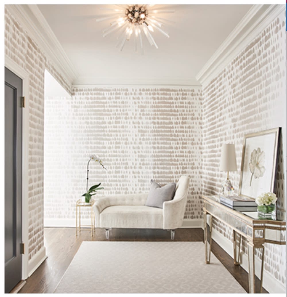 This foyer makes a statement with tan and white patterned wallpaper, statement lighting and cream chaise.