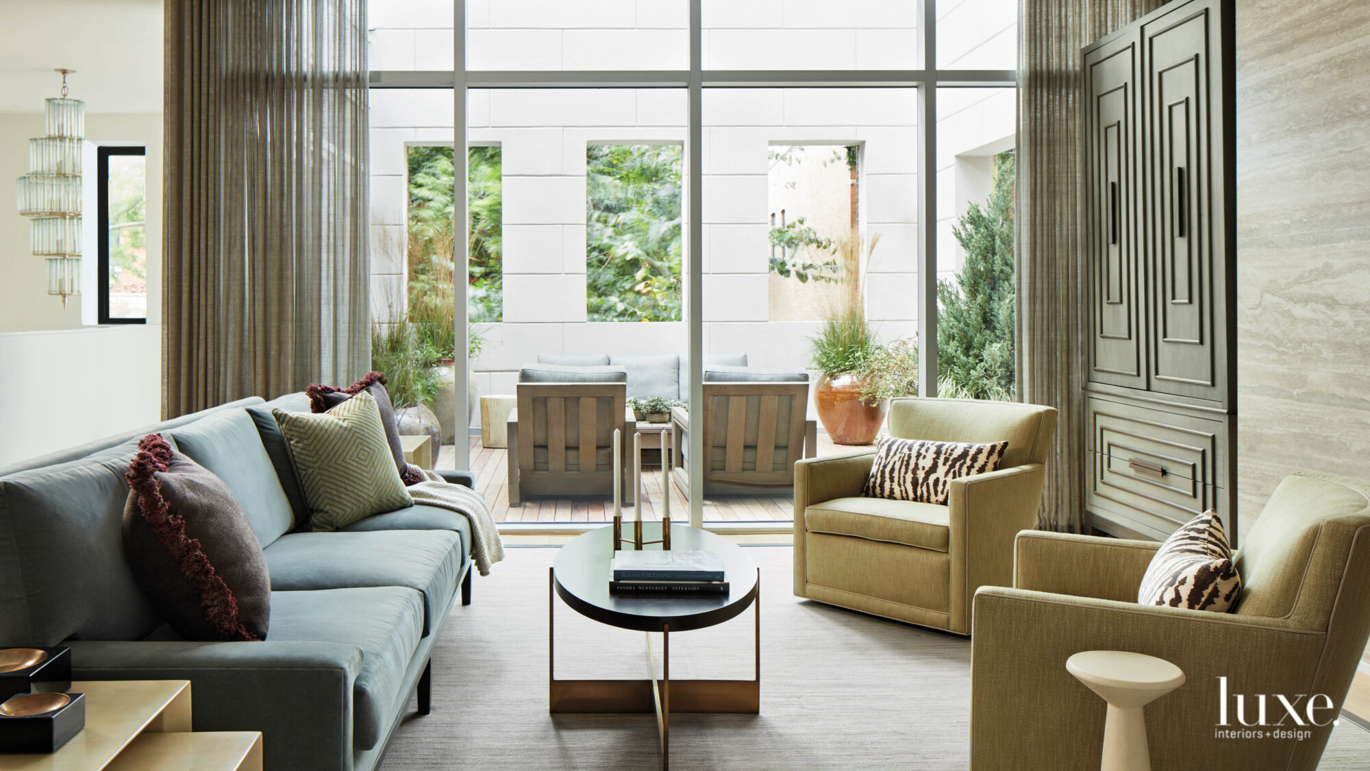 The living room, which is furnished with a gray-blue sofa and yellow-green armchairs looks out on a patio.