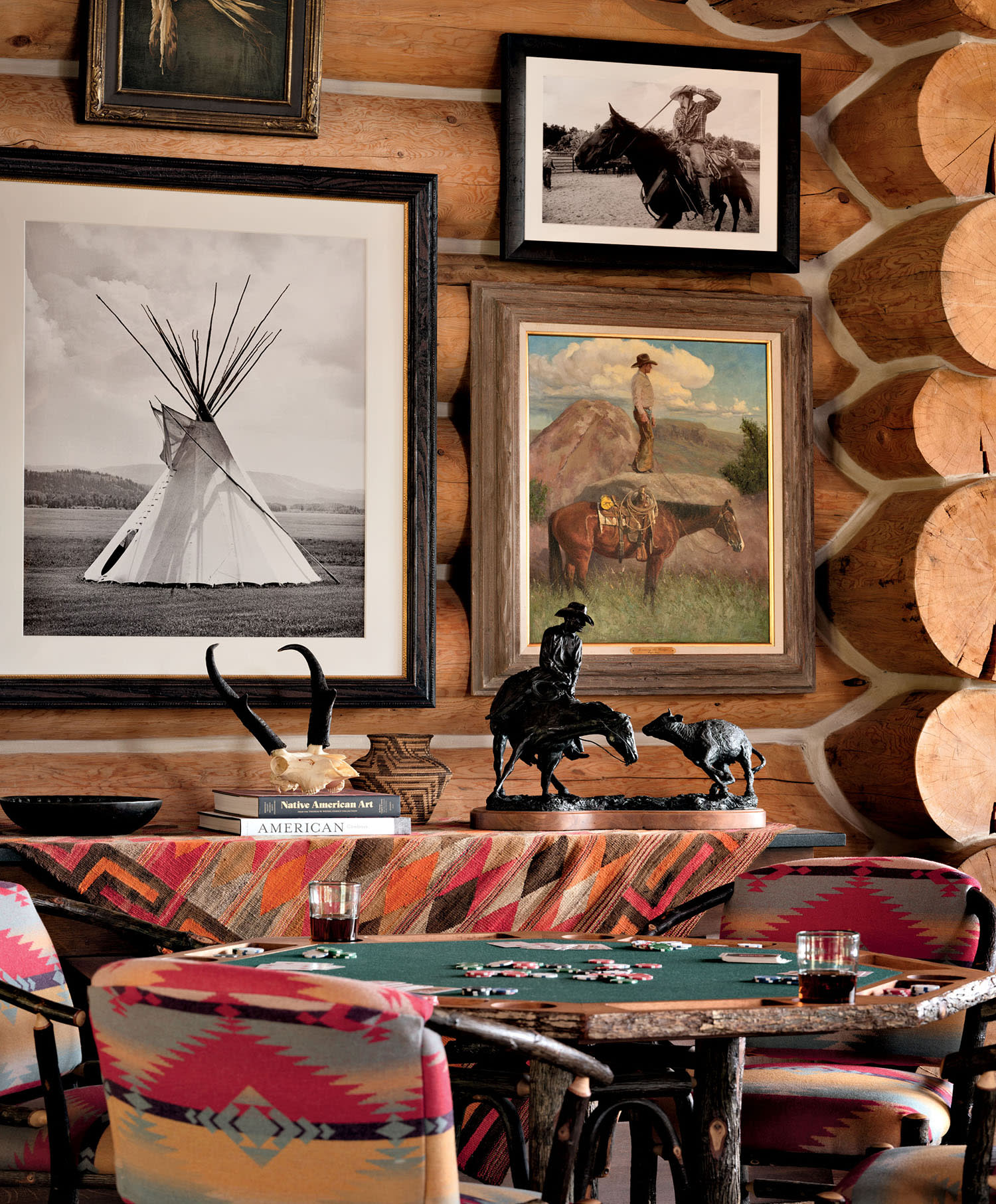 Photographs of different sizes hang on a wood wall behind a game table with brightly upholstered chairs