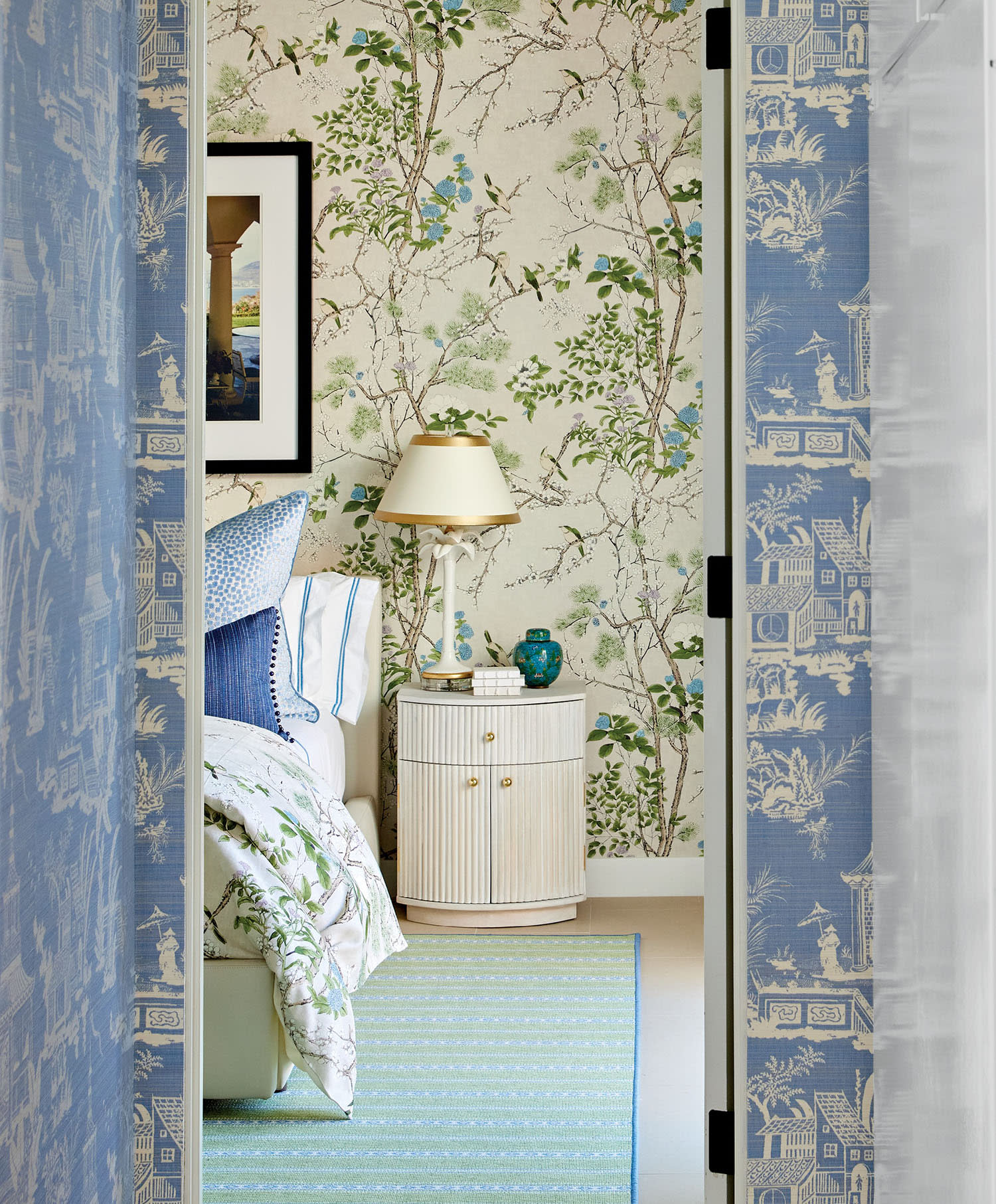 Hallway with blue patterned wallpaper leading to a bedroom. 