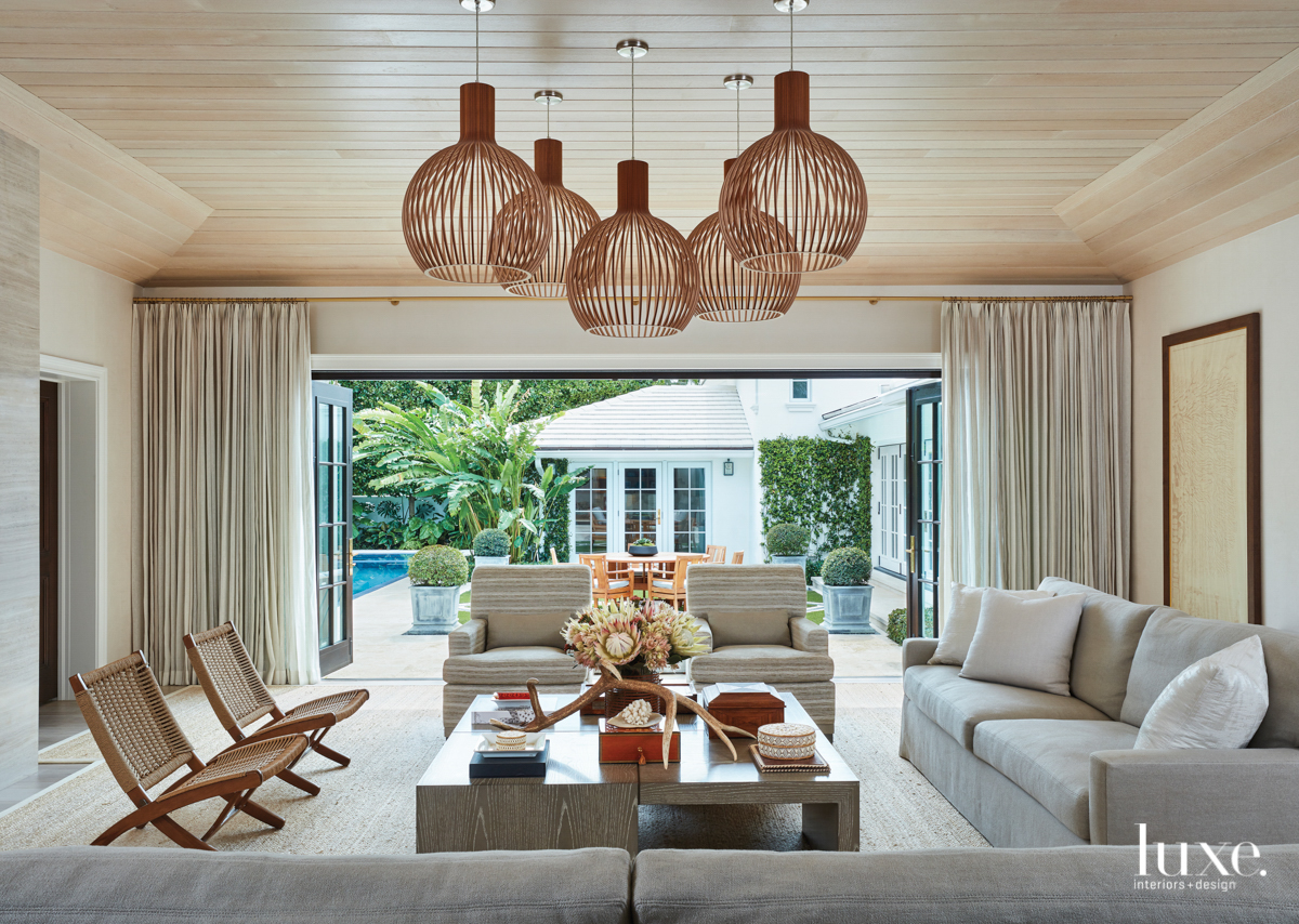 living room with open wall-to-wall dors and drapery with large wooden light fixtures